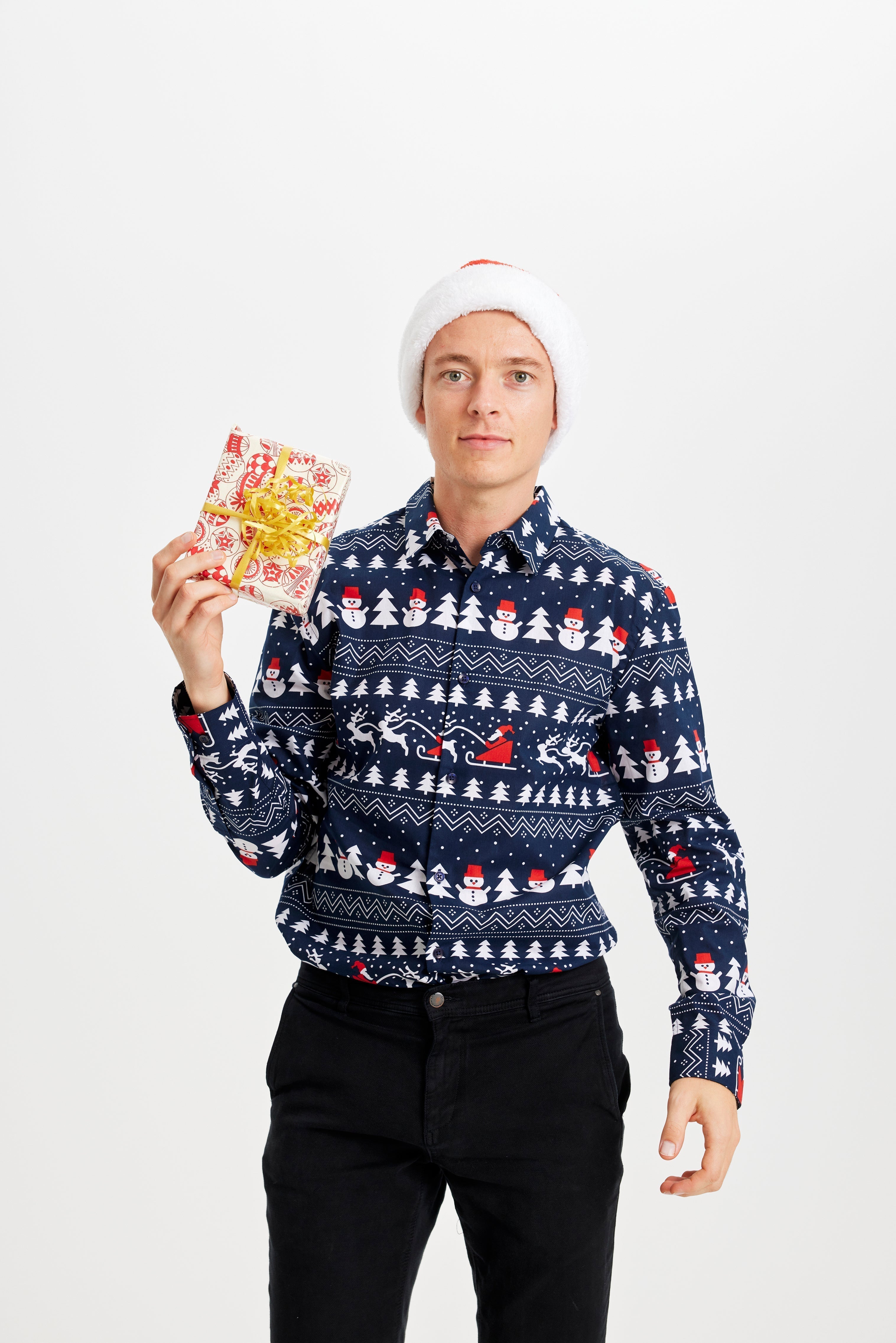 Un homme avec un cadeau portant une chemise de Noël bleue avec un motif.