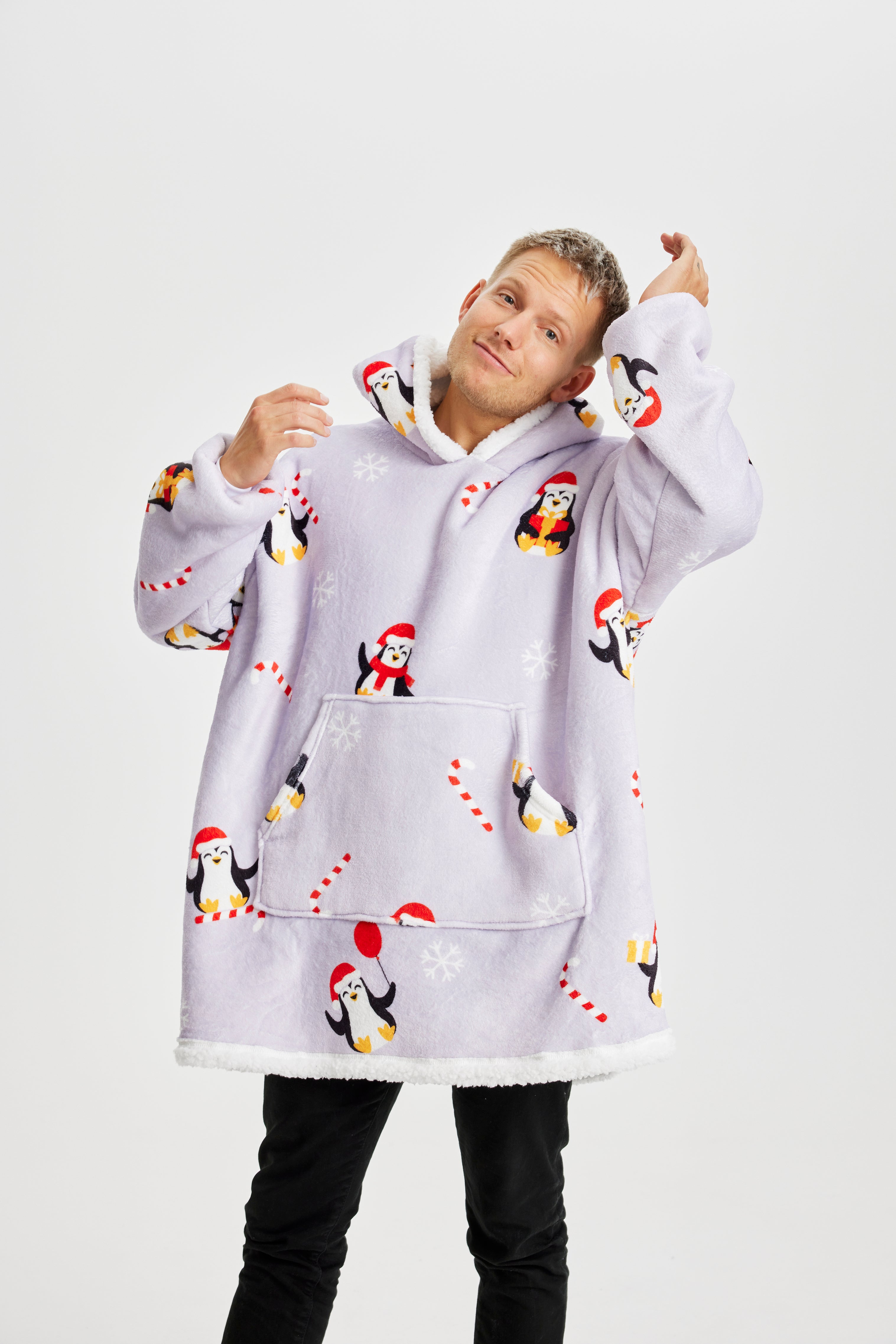 Un homme portant un sweat à capuche de Noël violet clair avec des pingouins dessus.