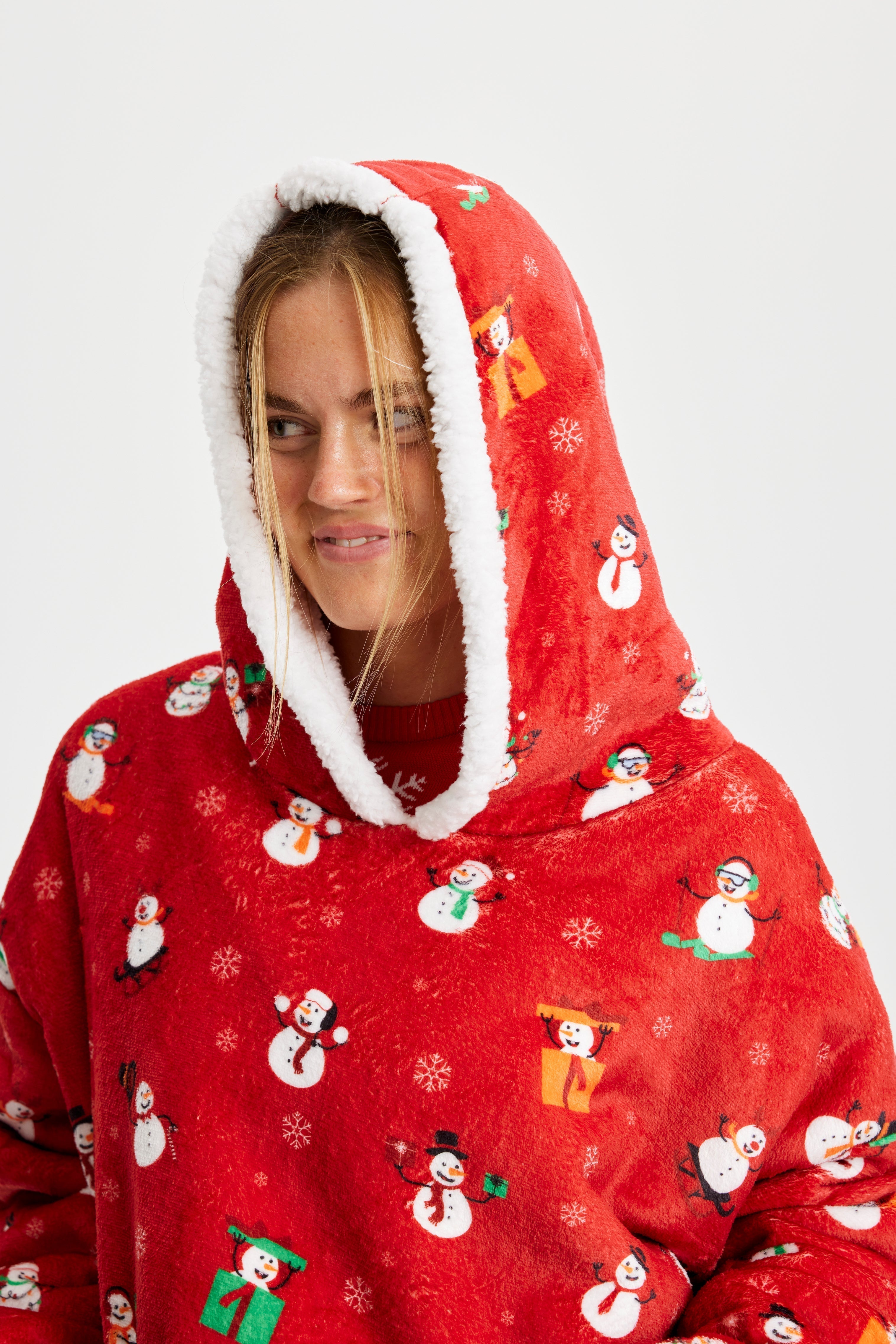 Une femme regarde de côté et porte un sweat à capuche rouge avec un motif de Noël.