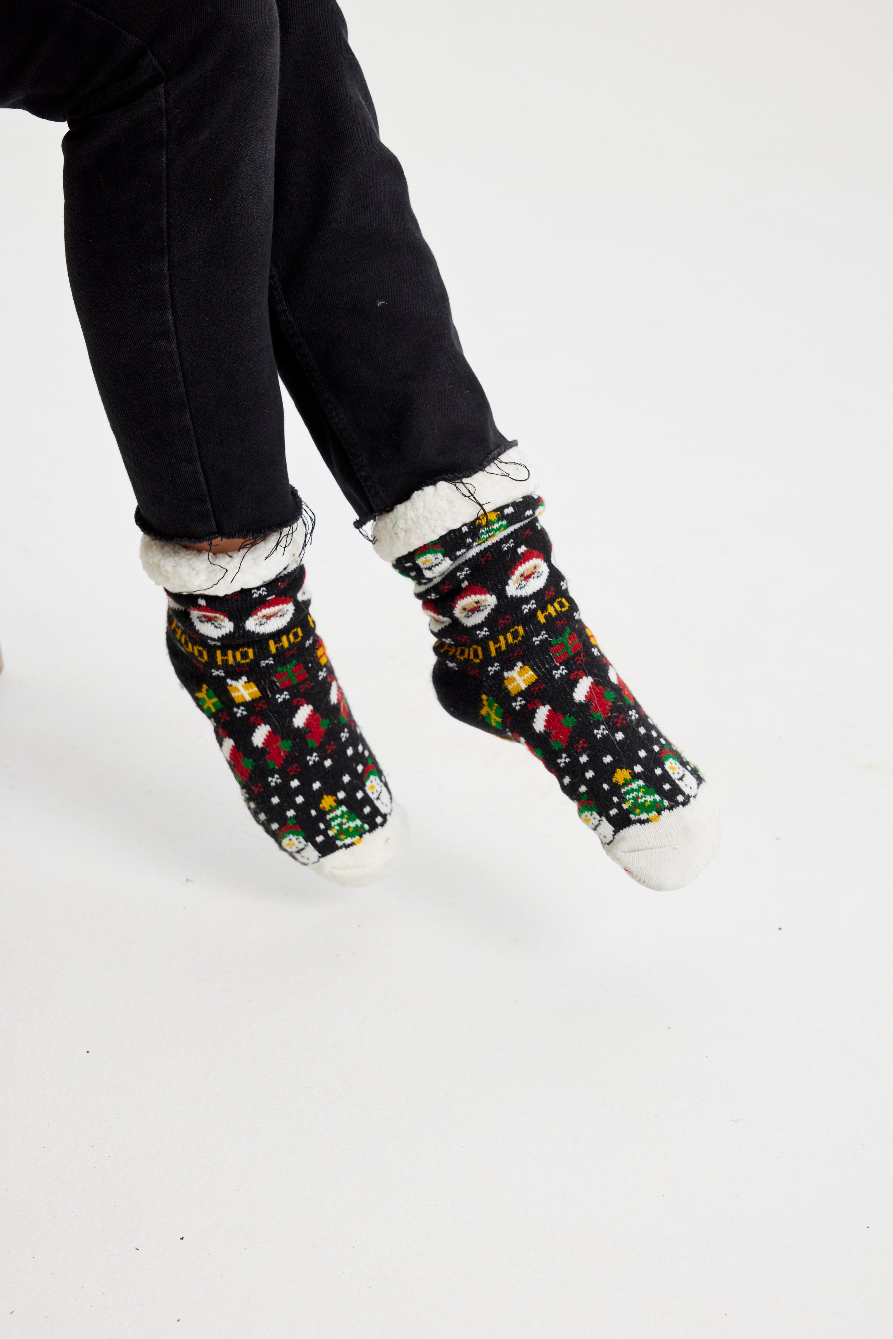 Une paire de pieds portant des chaussettes de Noël noires avec un motif de Noël.