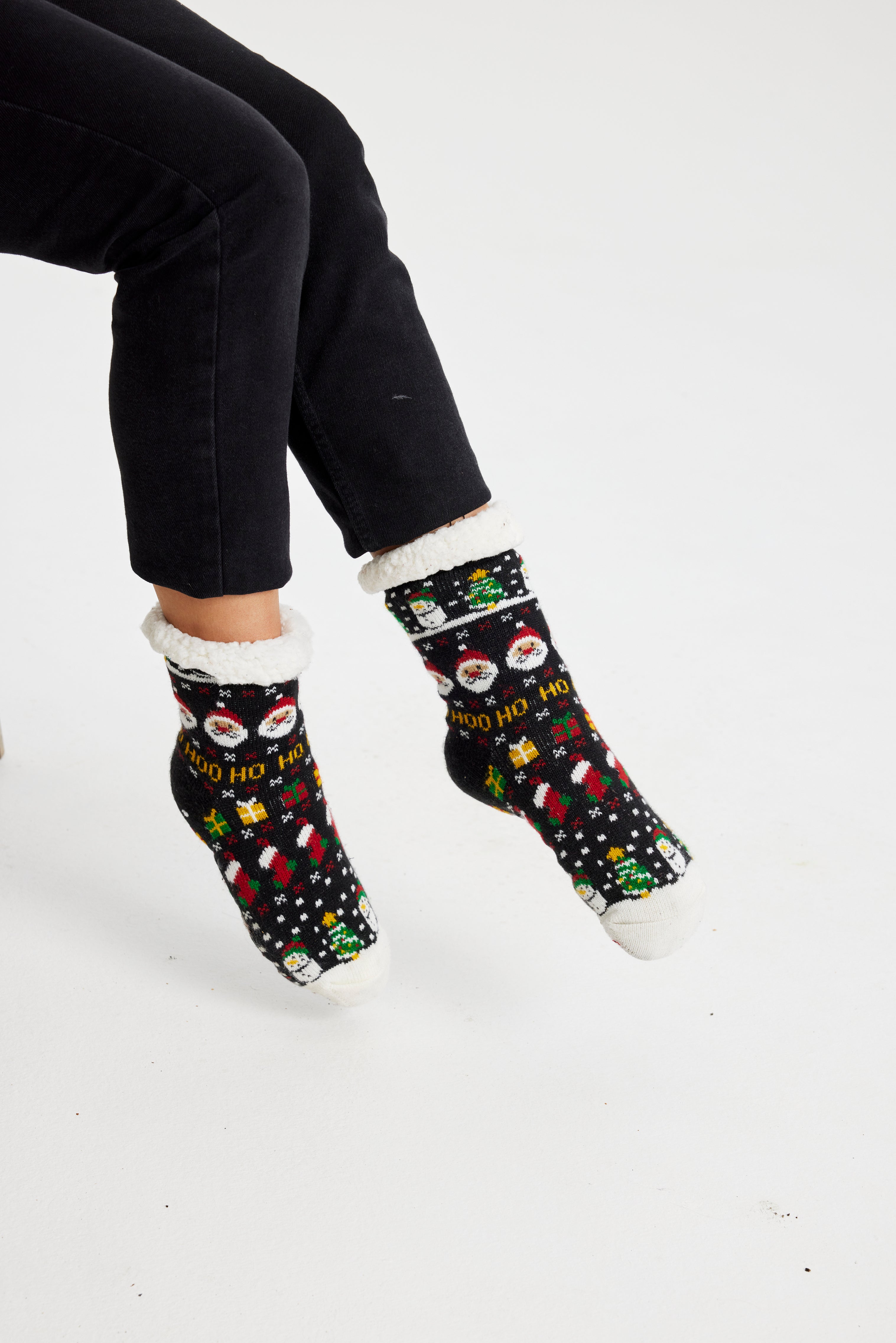Une paire de pieds portant des chaussettes de Noël noires avec un motif de Noël.