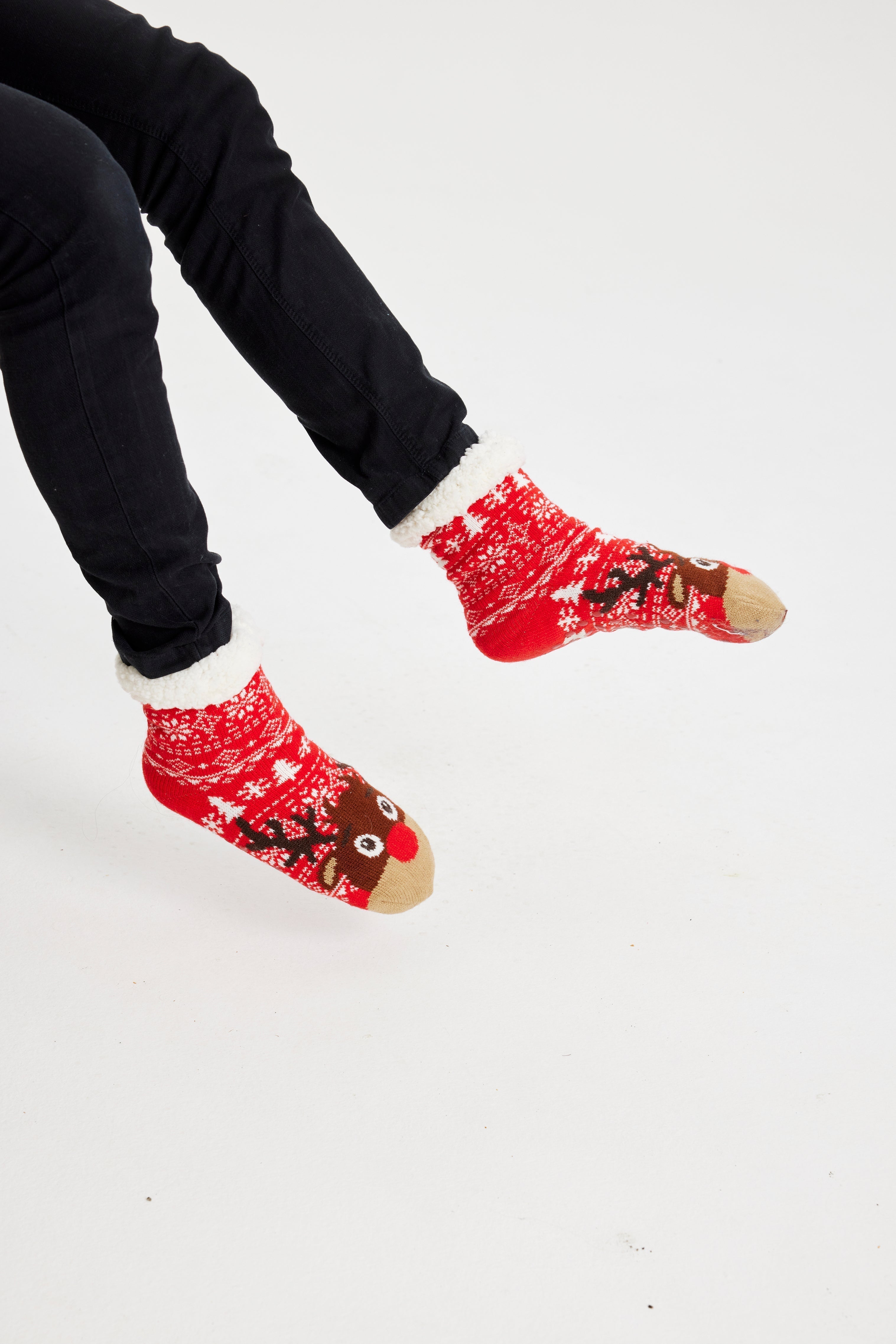 Une paire de pieds portant des chaussettes de Noël rouges ornées de Rudolph.