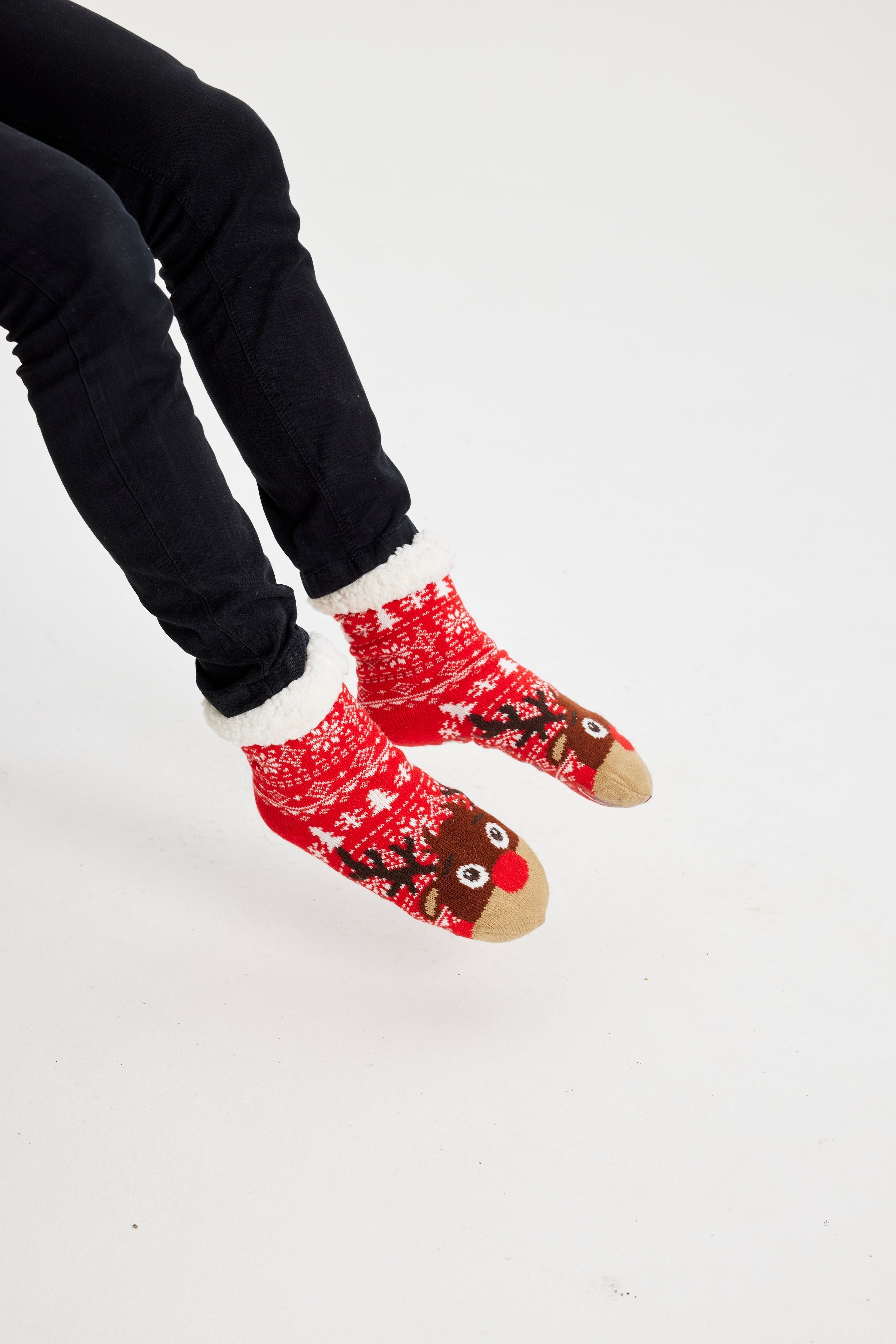 Une paire de pieds portant des chaussettes de Noël rouges ornées de Rudolph.