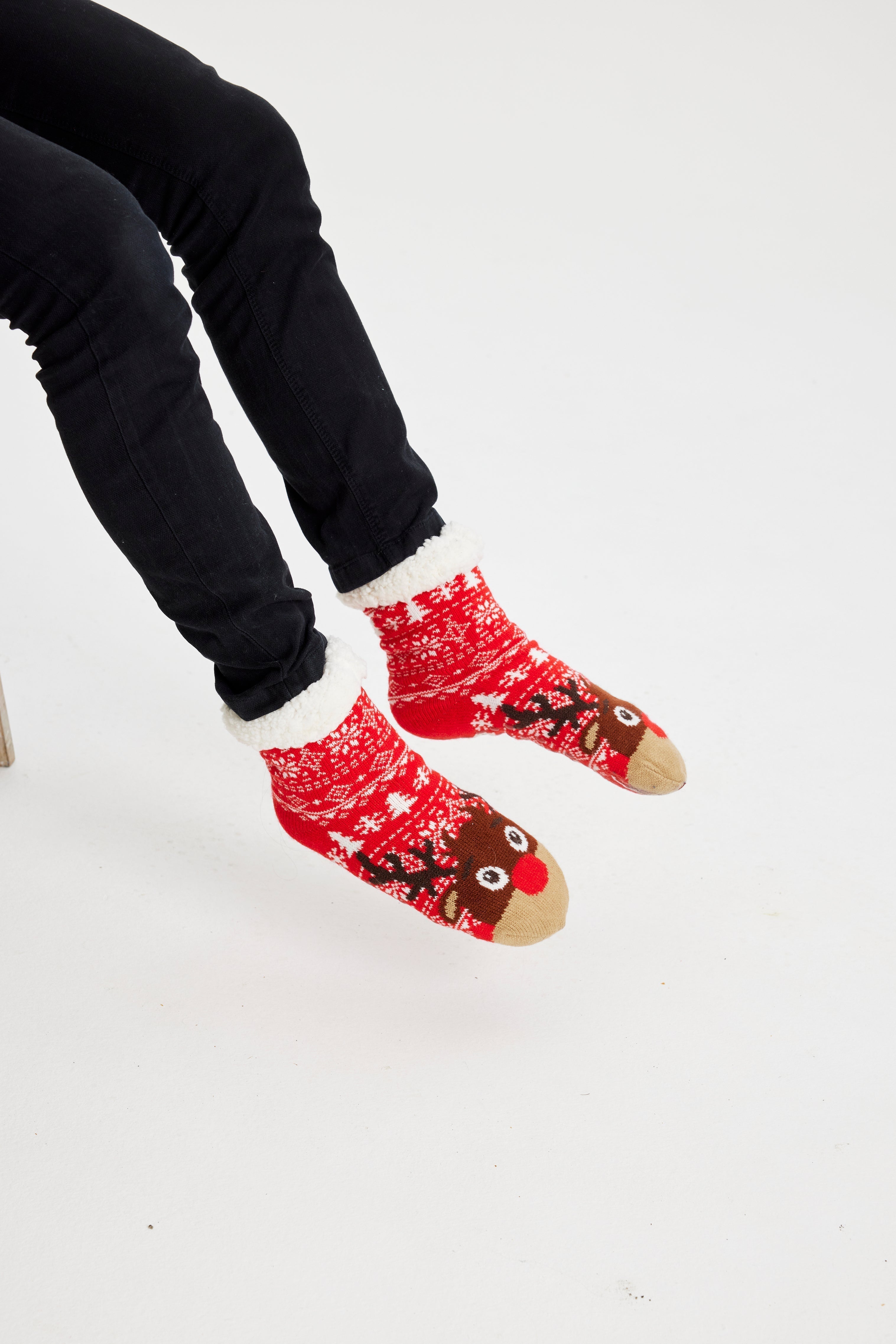 Une paire de pieds portant des chaussettes de Noël rouges ornées de Rudolph.