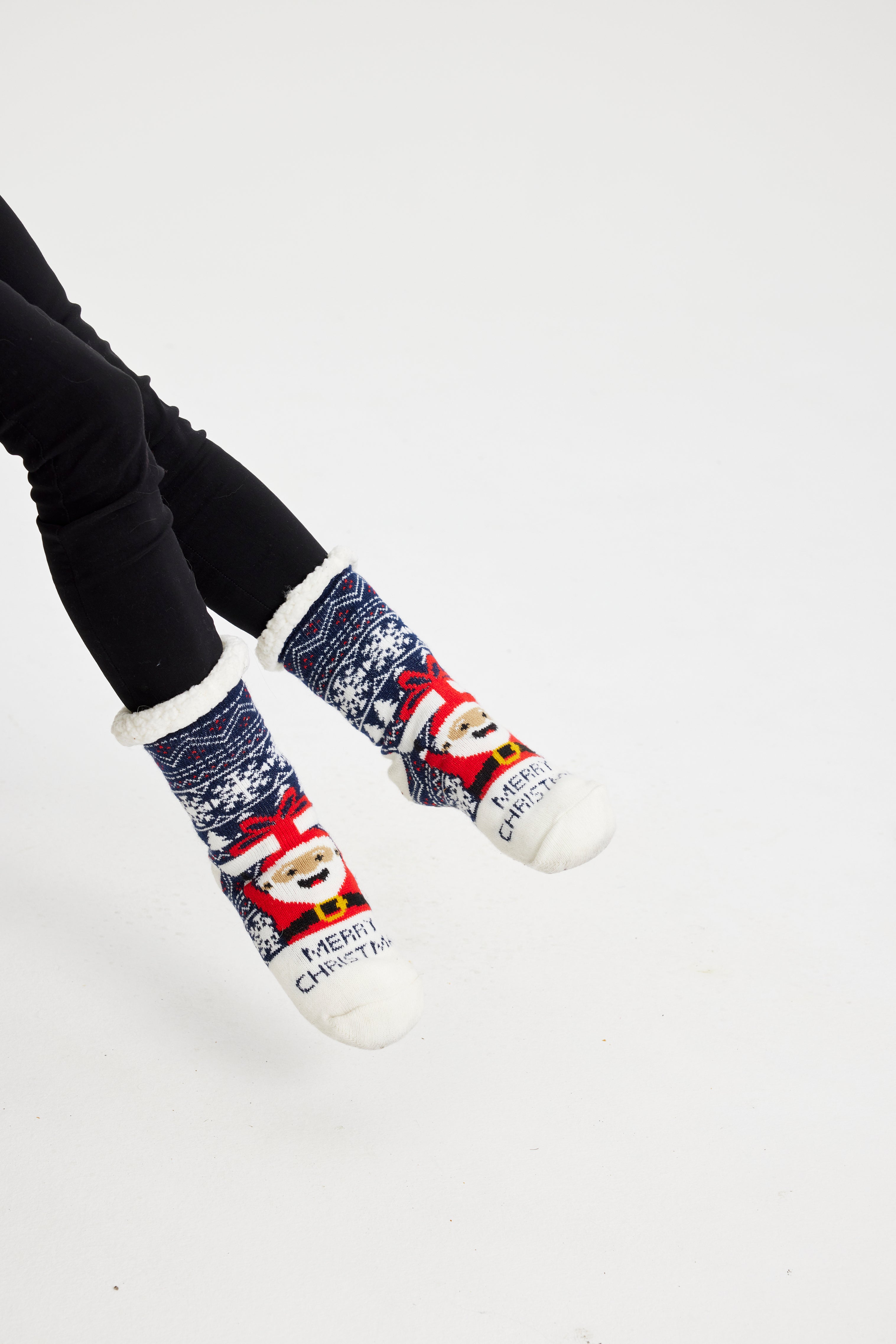 Une paire de pieds portant des chaussettes de Noël bleues avec un Père Noël dessus.