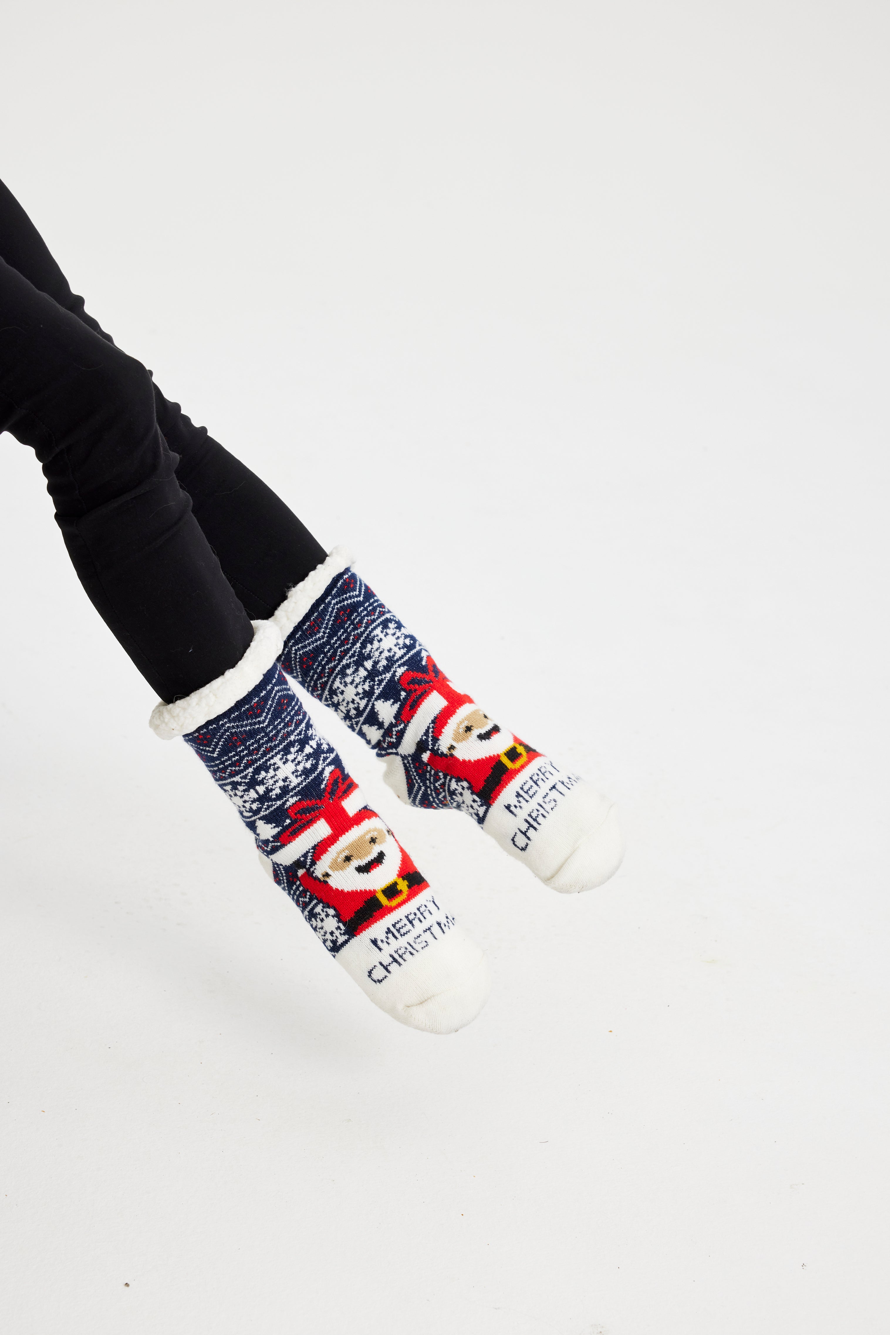 Une paire de pieds portant des chaussettes de Noël bleues avec un Père Noël dessus.