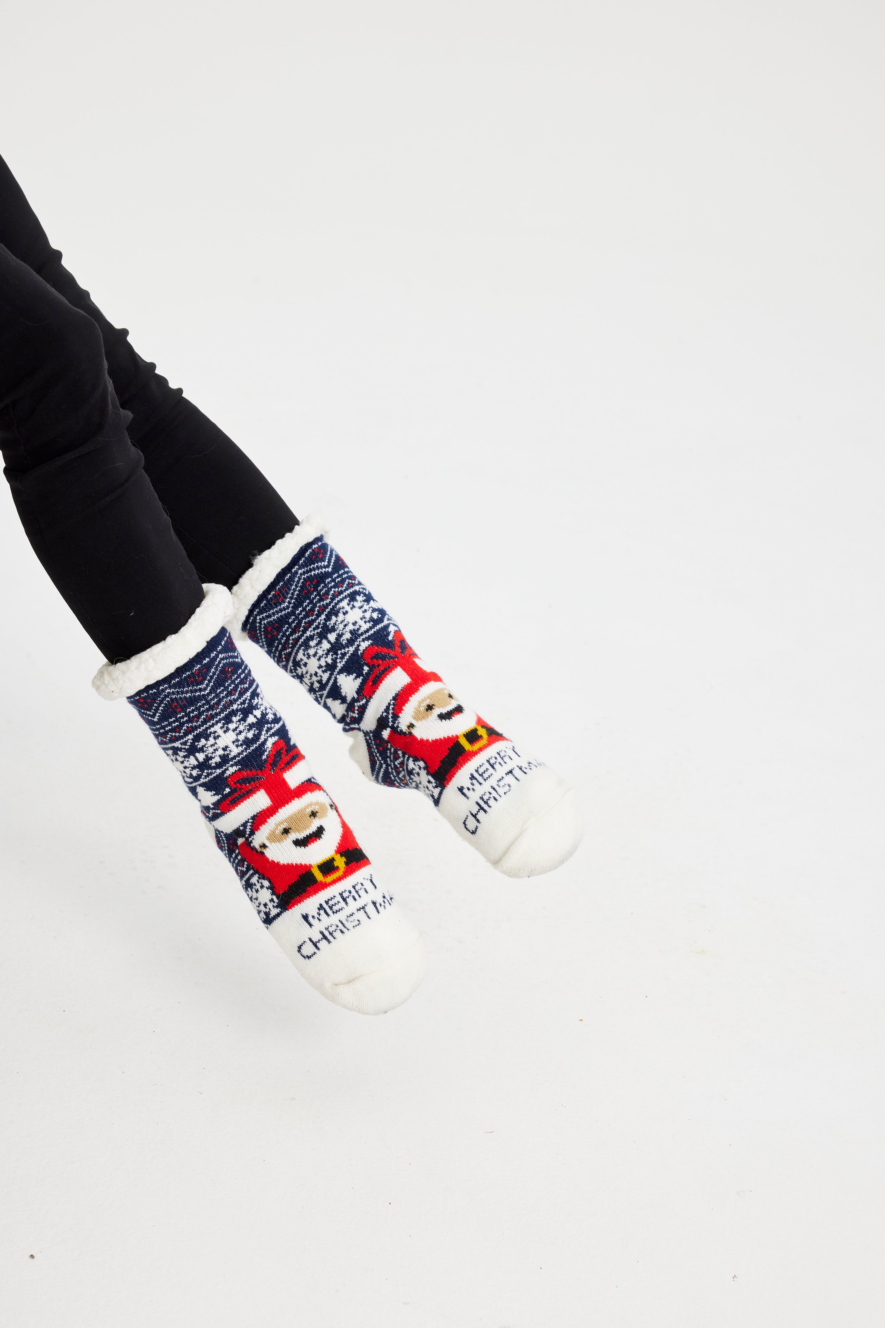 Une paire de pieds portant des chaussettes de Noël bleues avec un Père Noël dessus.