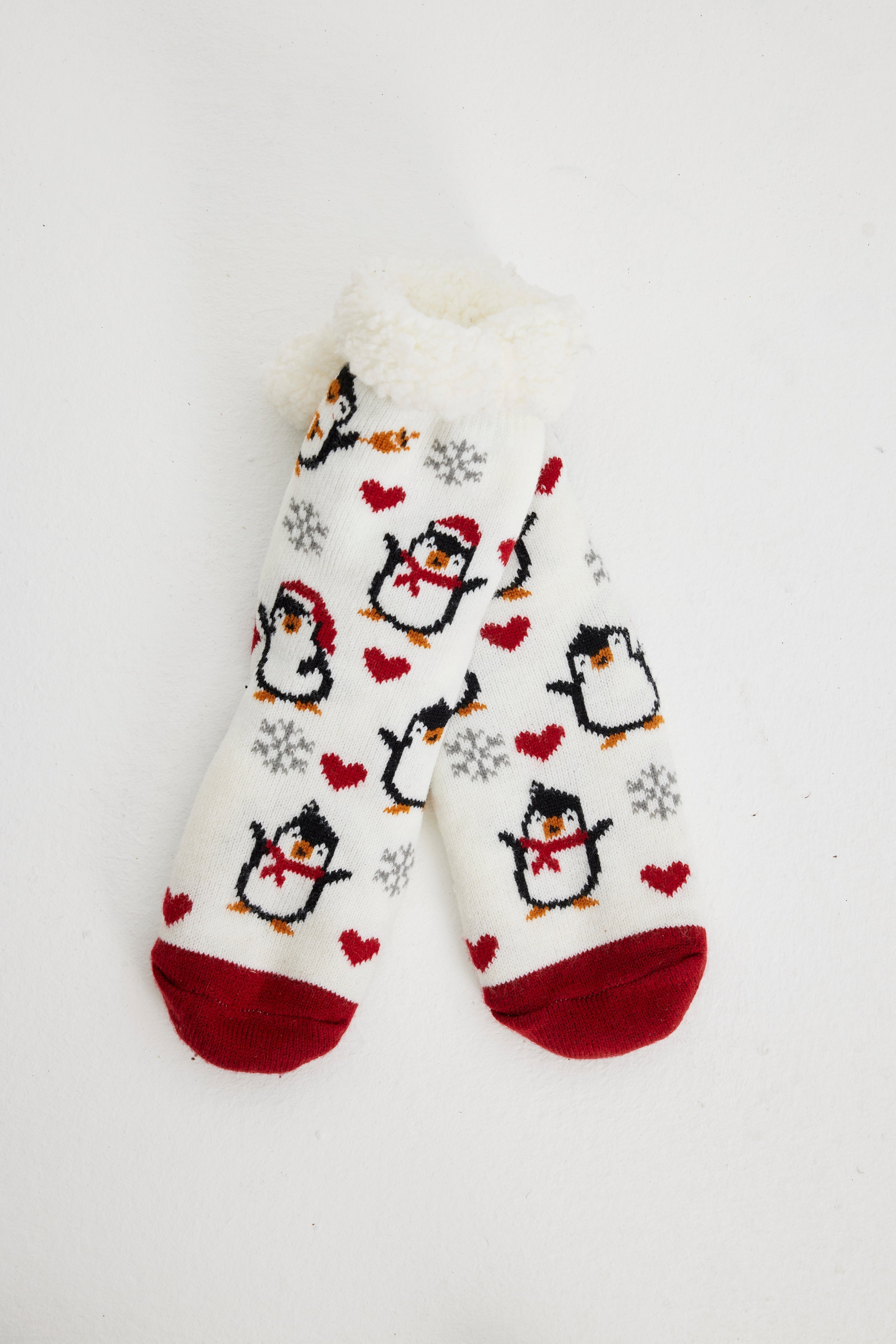 Une paire de chaussettes de Noël rouges et blanches ornées de pingouins.