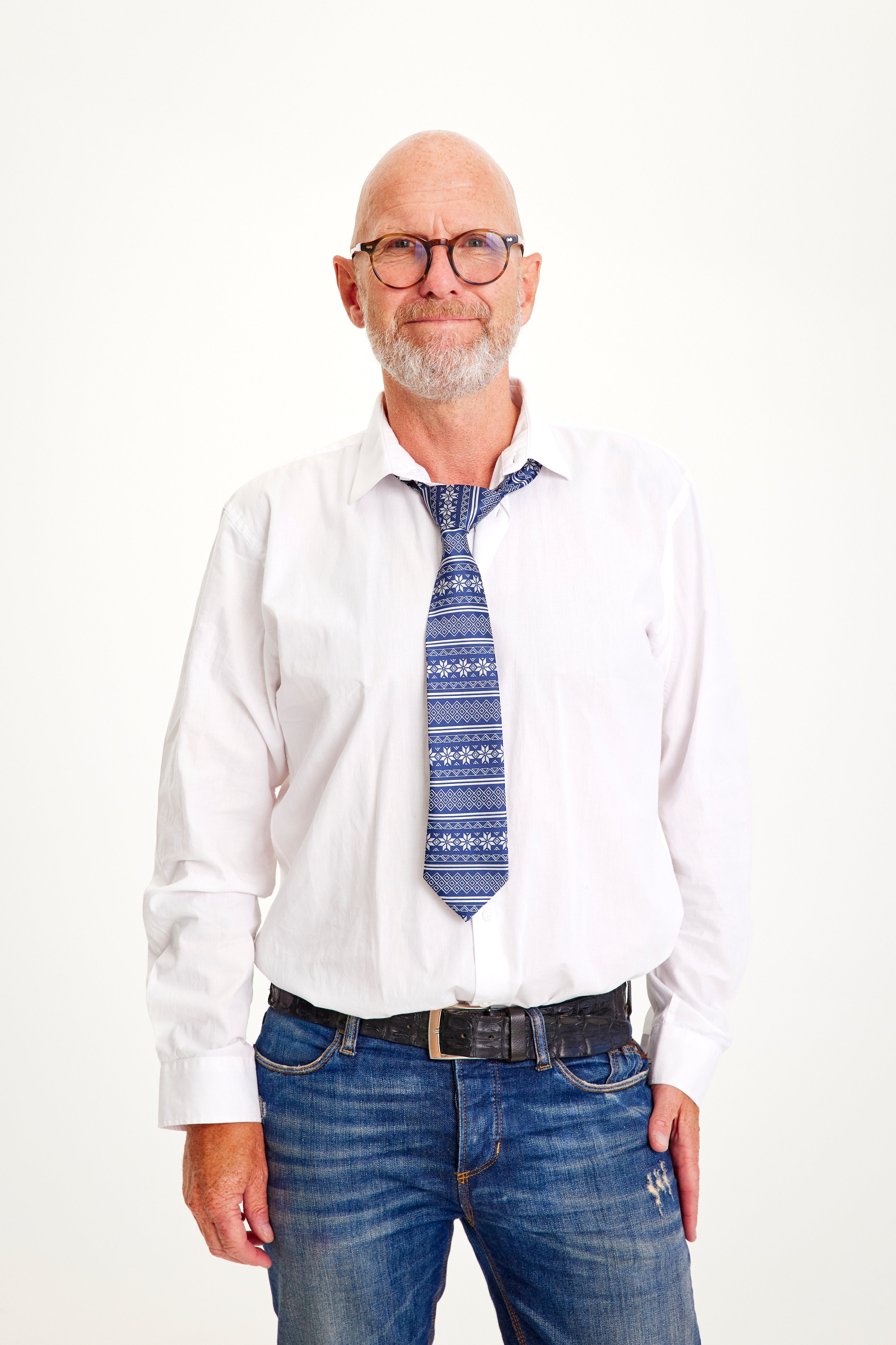 Un homme souriant en chemise blanche portant une cravate bleue de Noël.