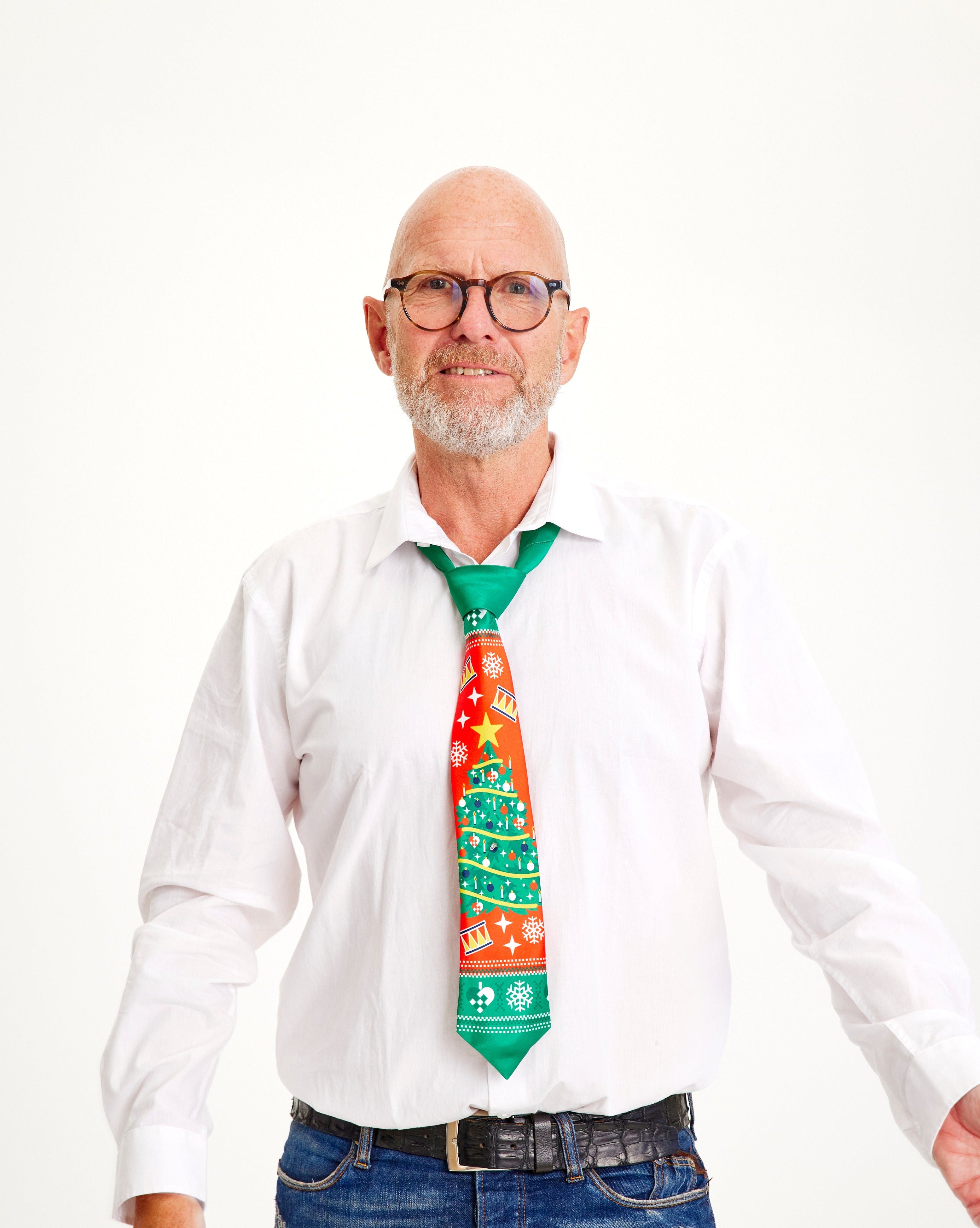 Un homme en chemise blanche portant une cravate de Noël à motifs rouges et verts.