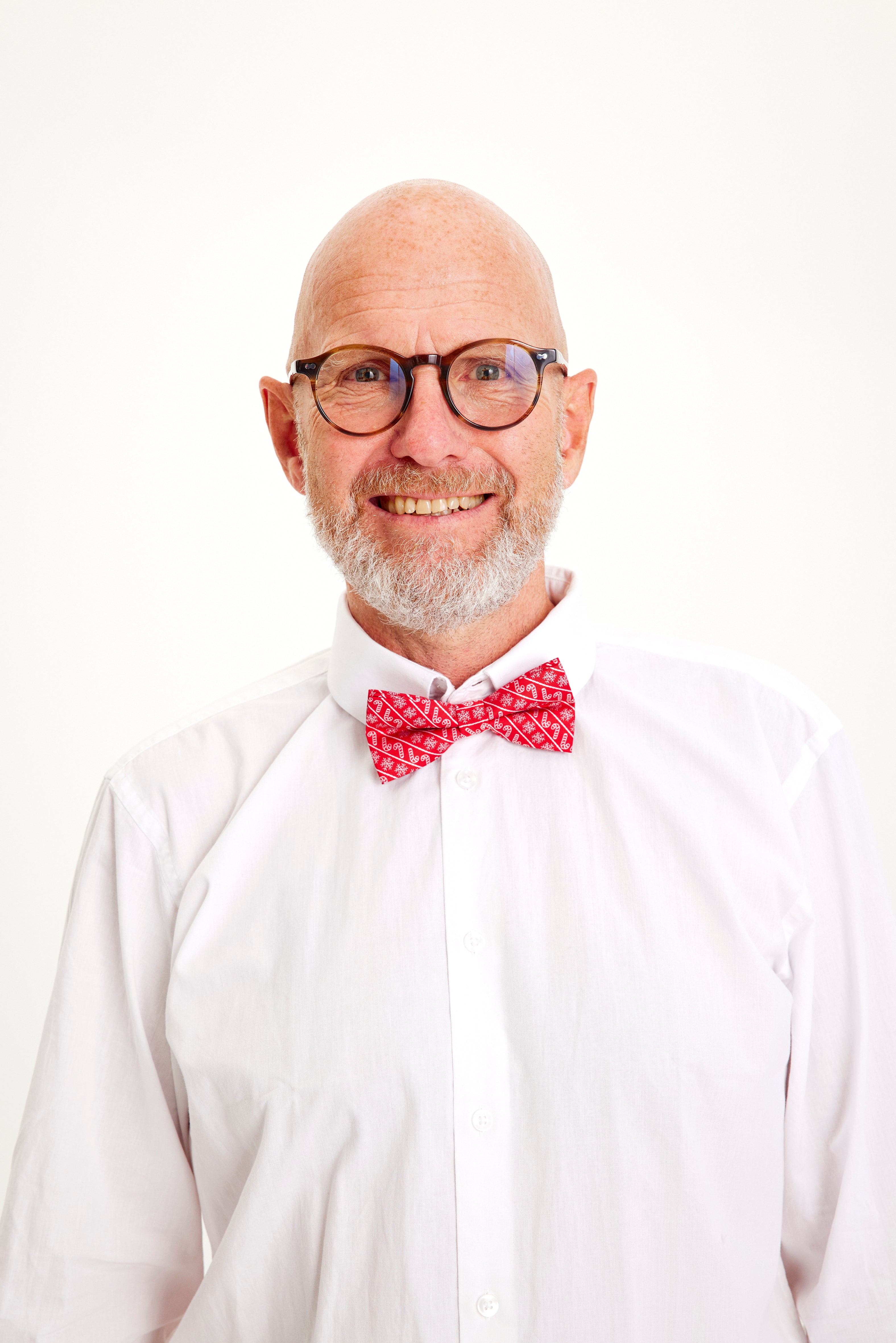 Un homme souriant portant un nœud papillon rouge.