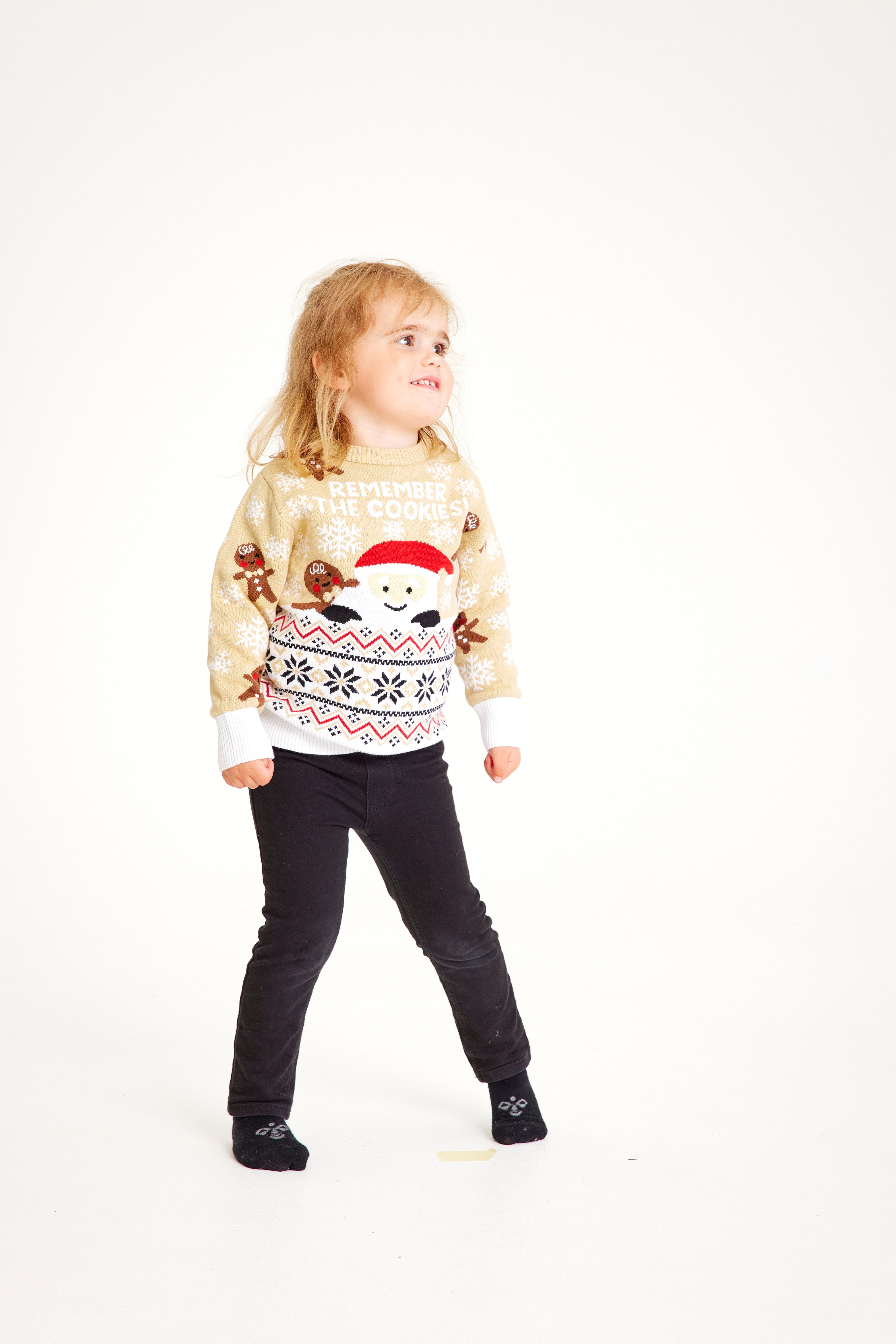 Un enfant portant un pull de Noël beige.