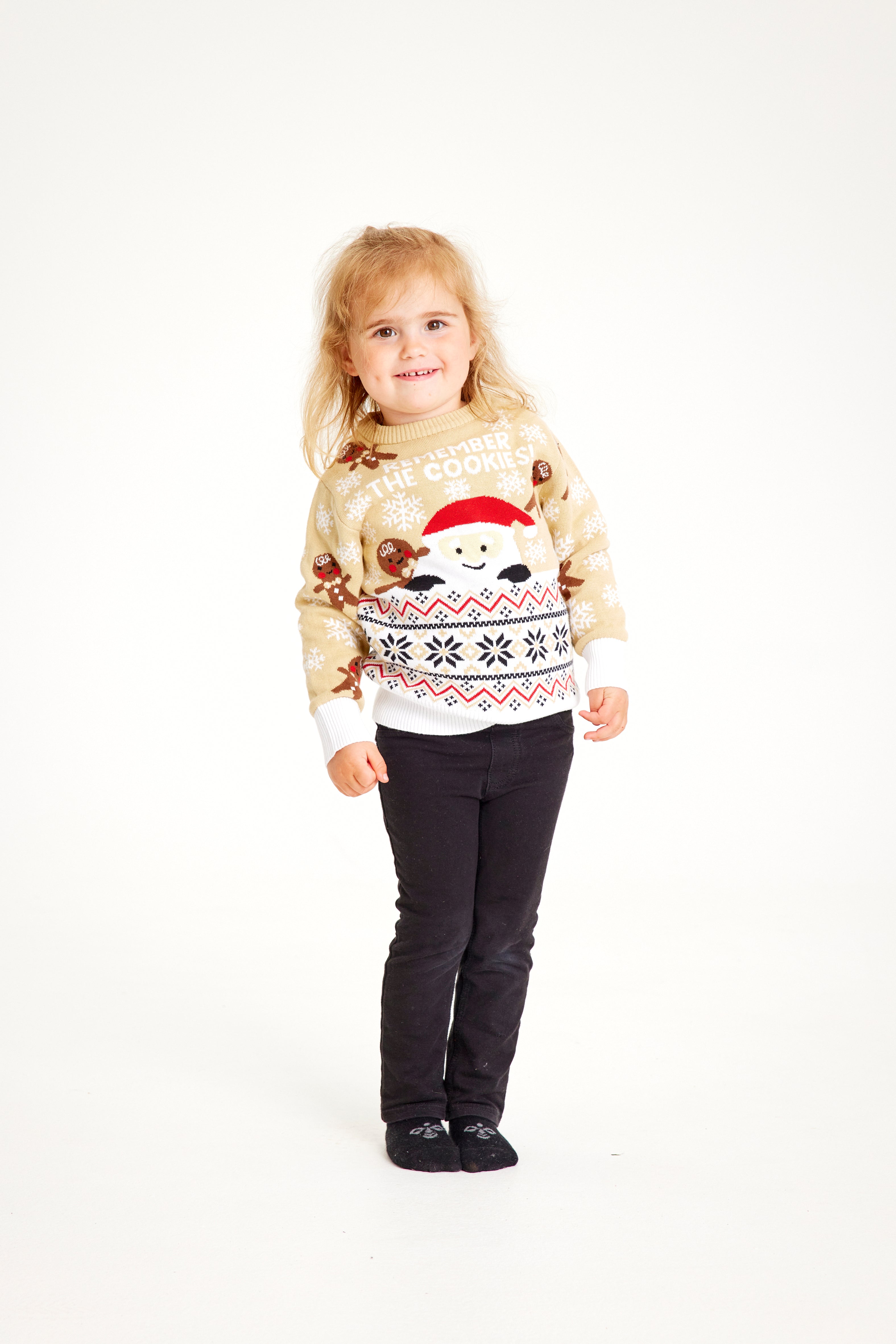 Enfant posant avec un pull de Noël beige.