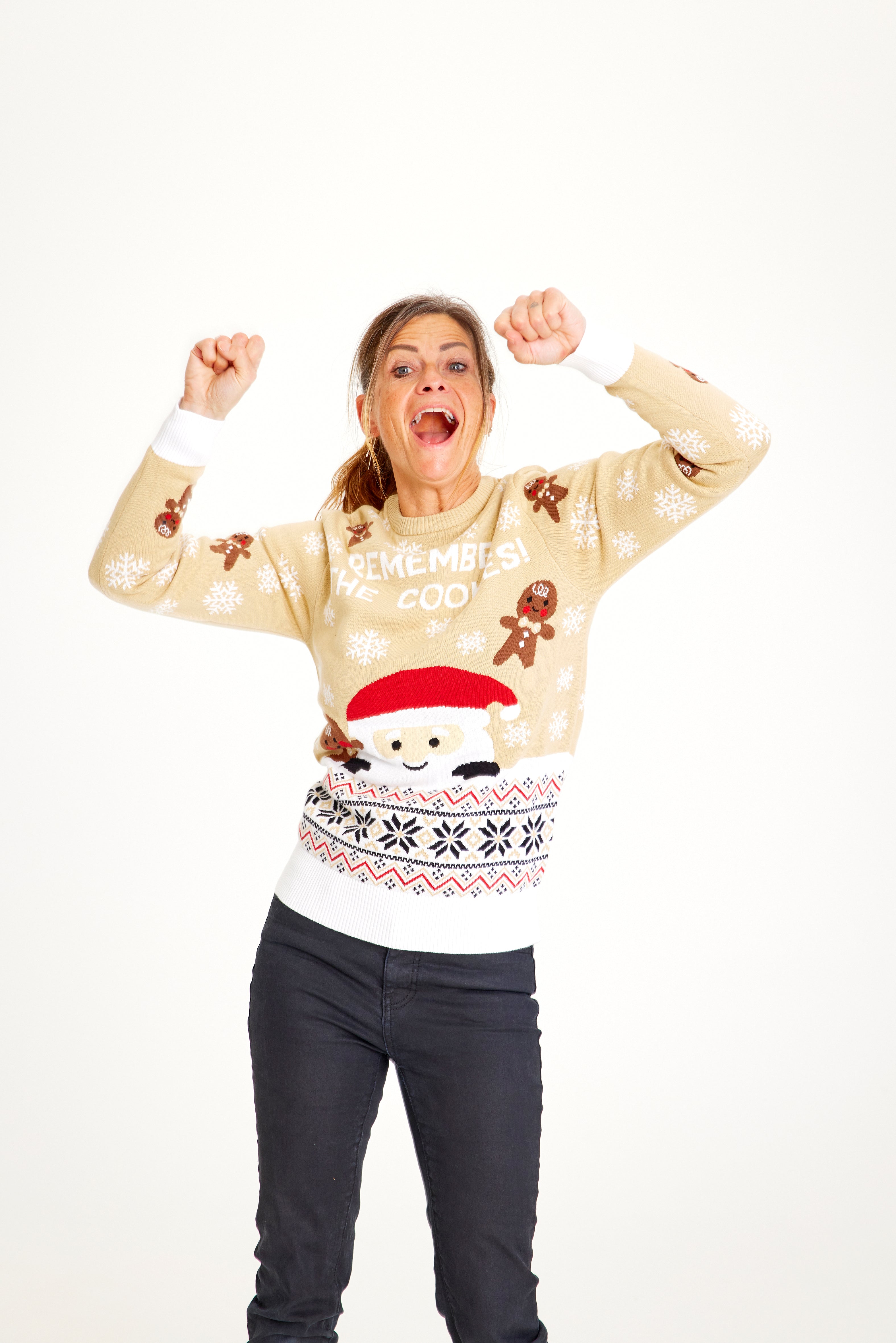 Une femme posant avec un pull de Noël beige.