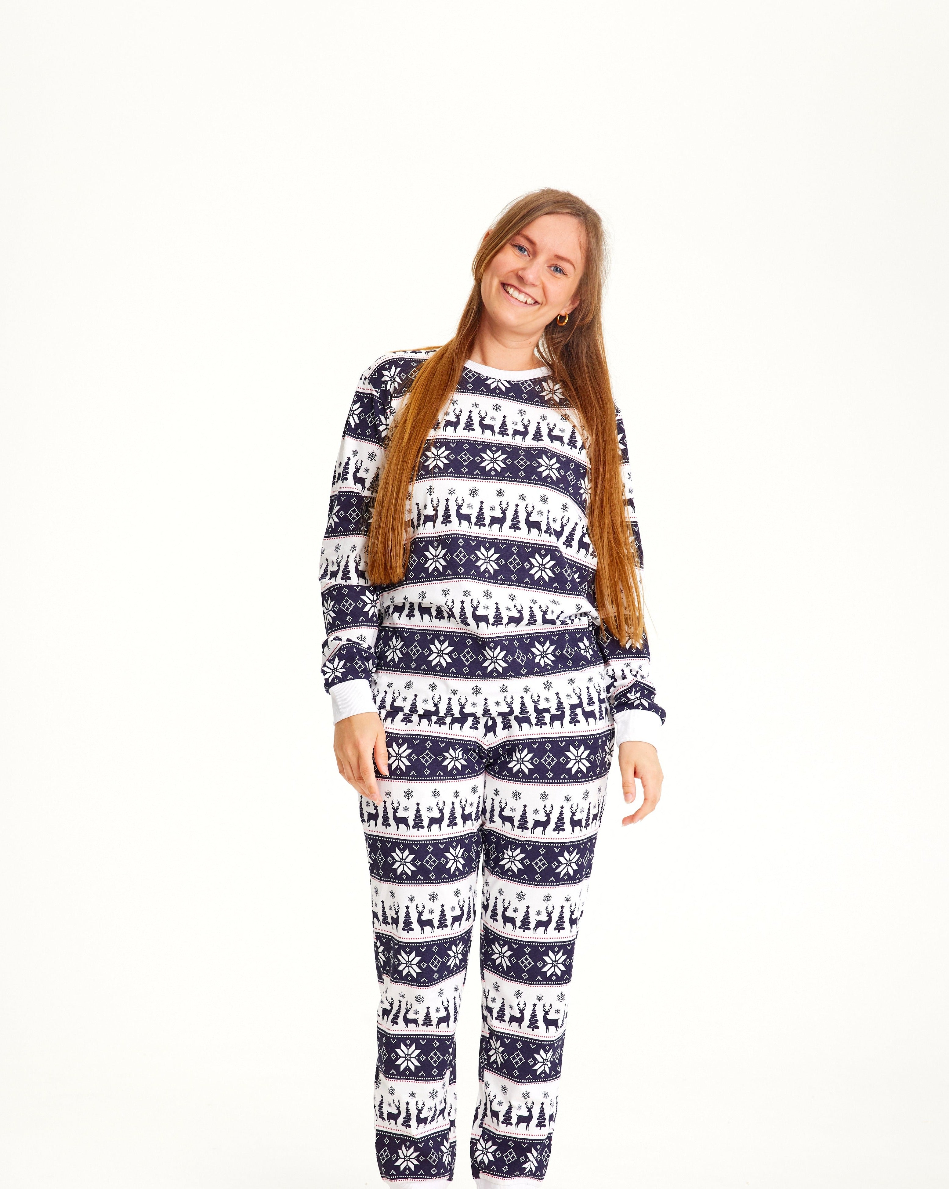 Une femme souriante portant un pyjama de Noël rayé blanc et bleu.