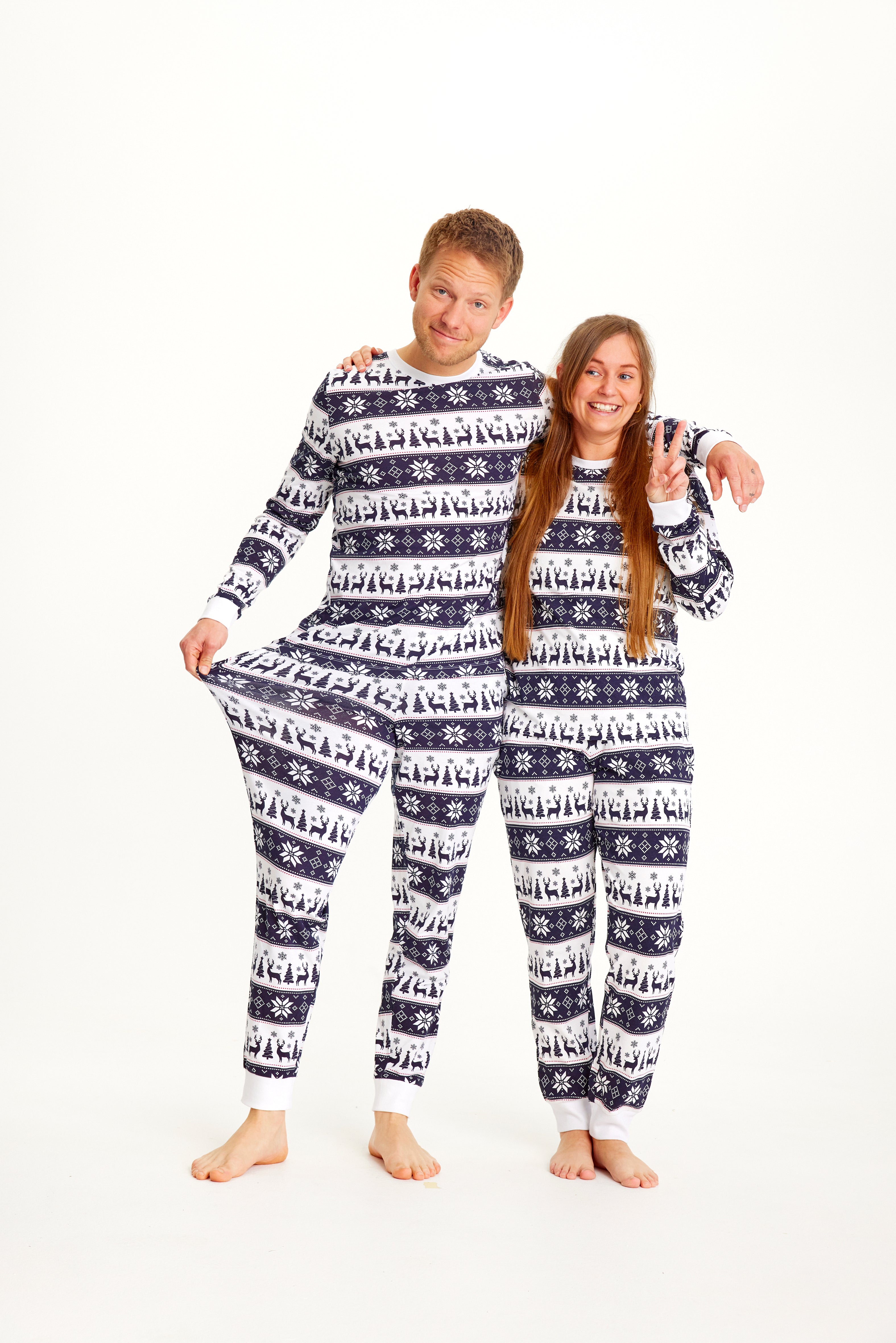 Un couple posant vêtu d'un pyjama de Noël à rayures blanches et bleues.