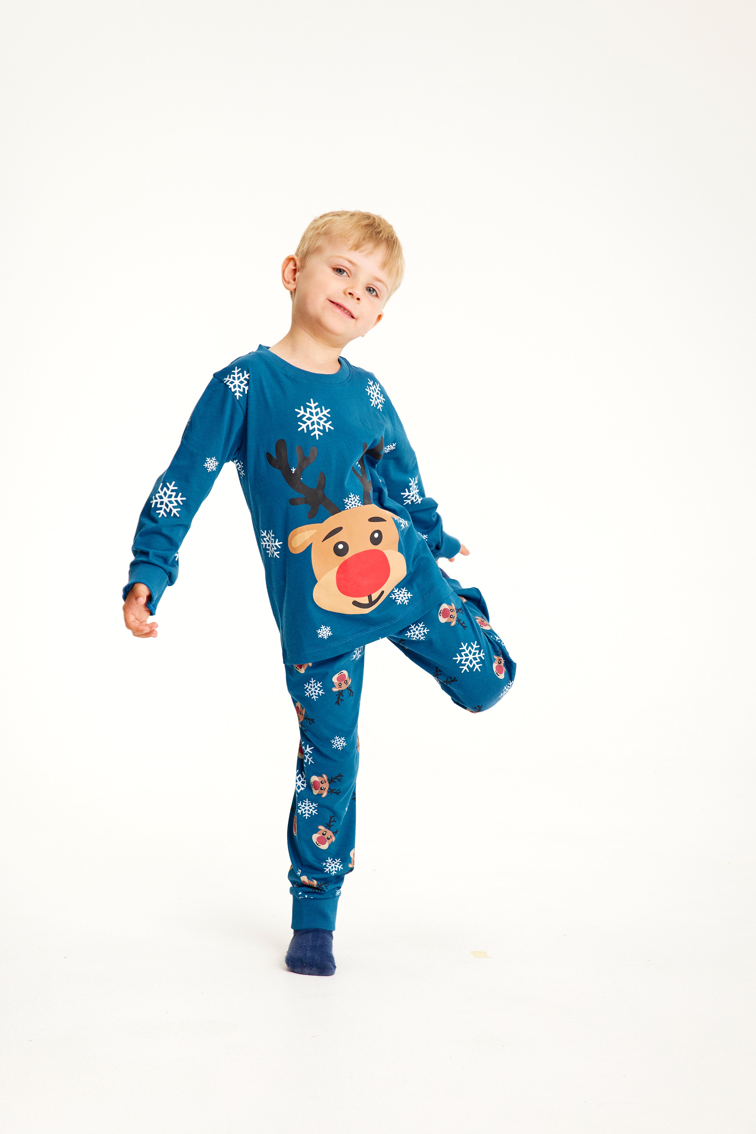 Un enfant sur une jambe portant un pyjama de Noël bleu avec Rudolph dessus.