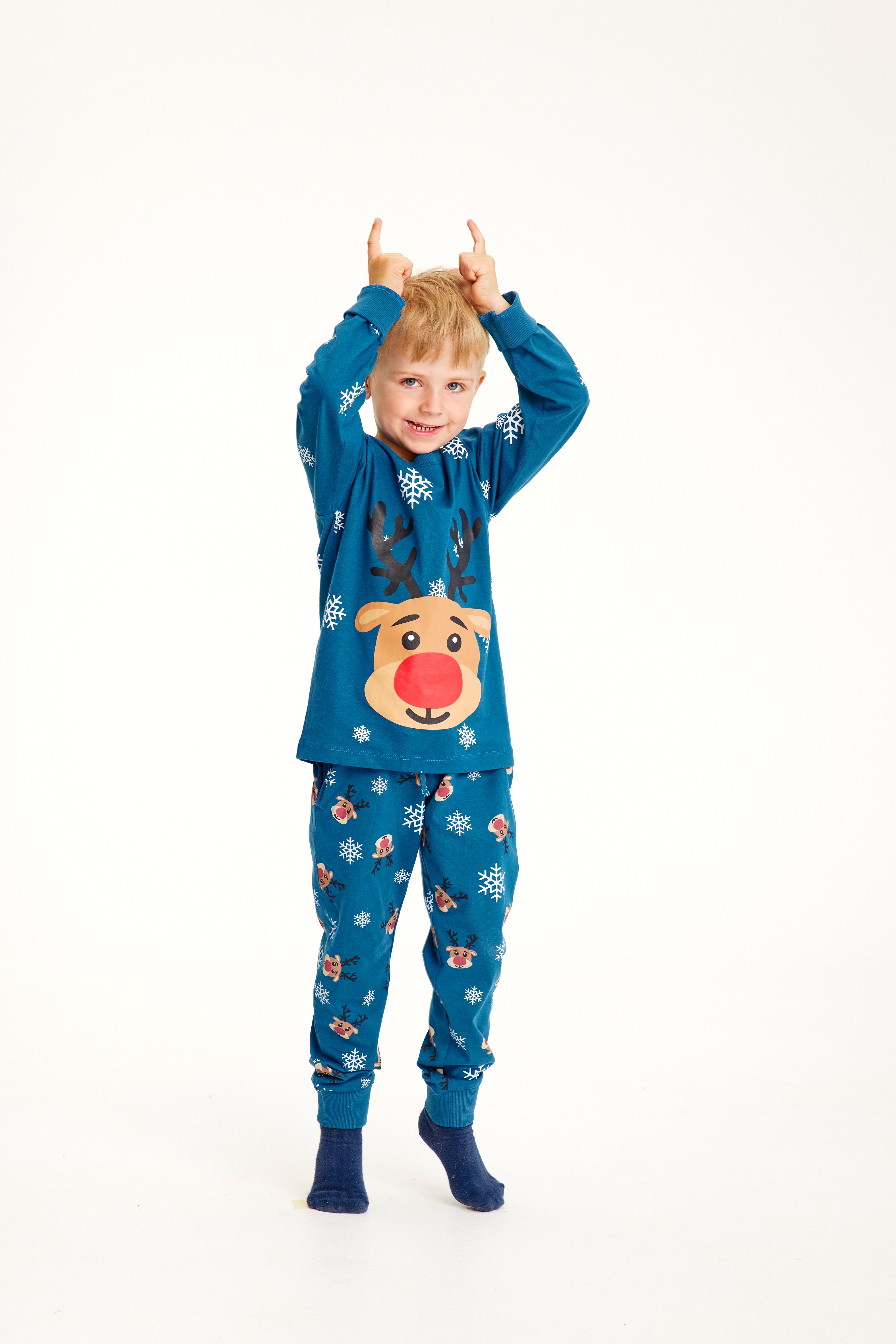 Un enfant posant avec un pyjama de Noël bleu avec Rudolph.