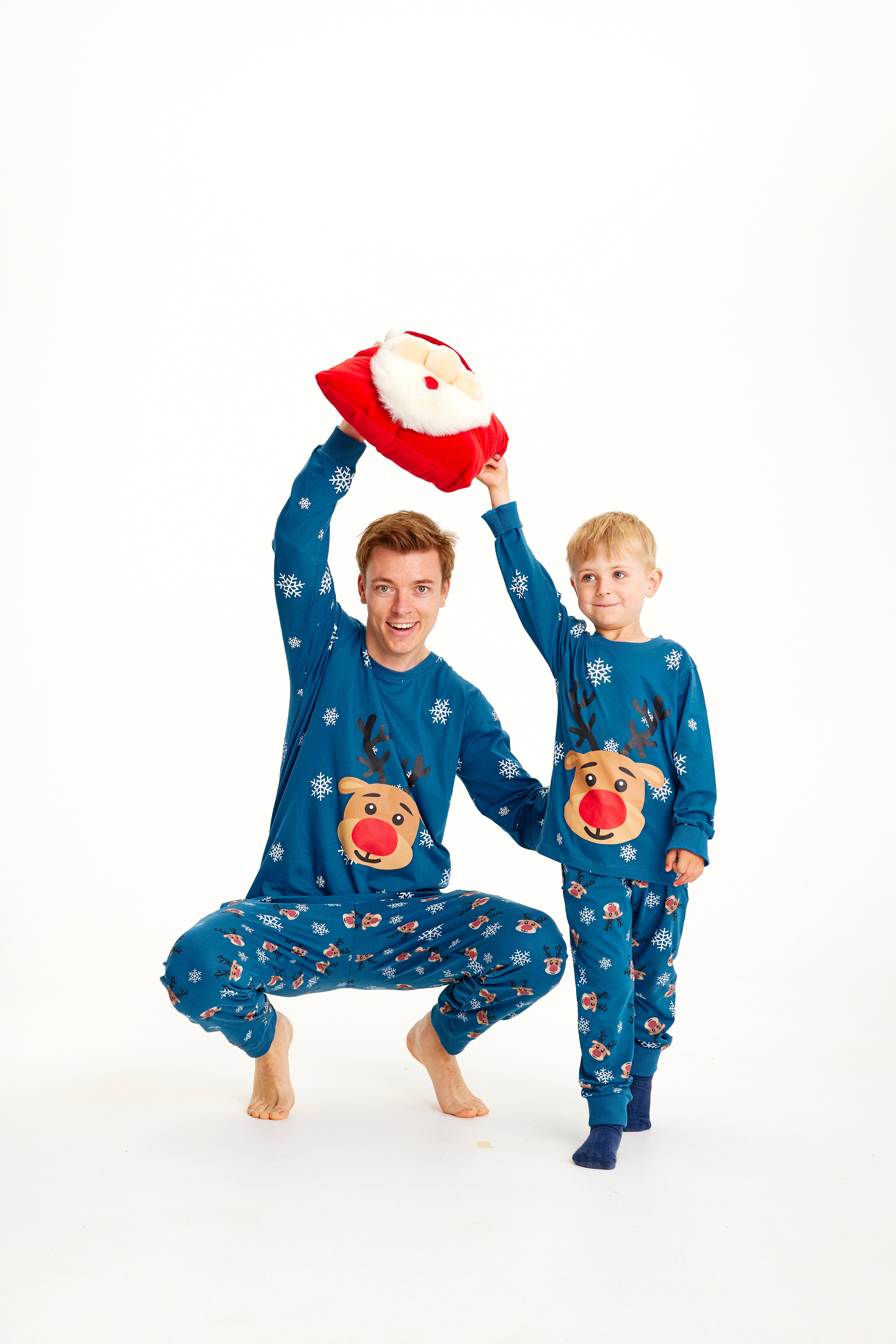 Un enfant et un homme portant un pyjama de Noël bleu orné de Rudolph.