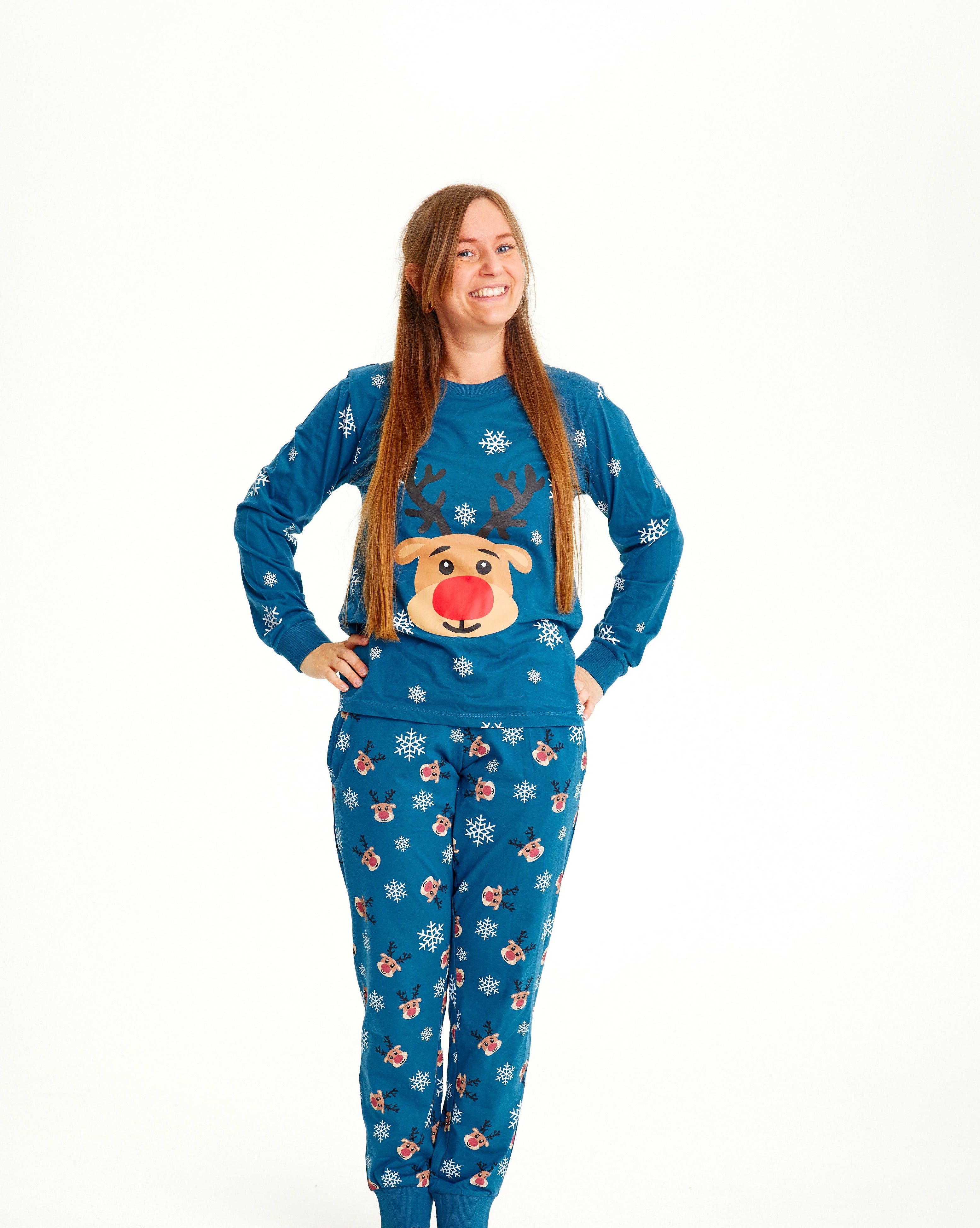 Une femme, les mains le long du corps, portant un pyjama de Noël bleu orné de Rudolph.