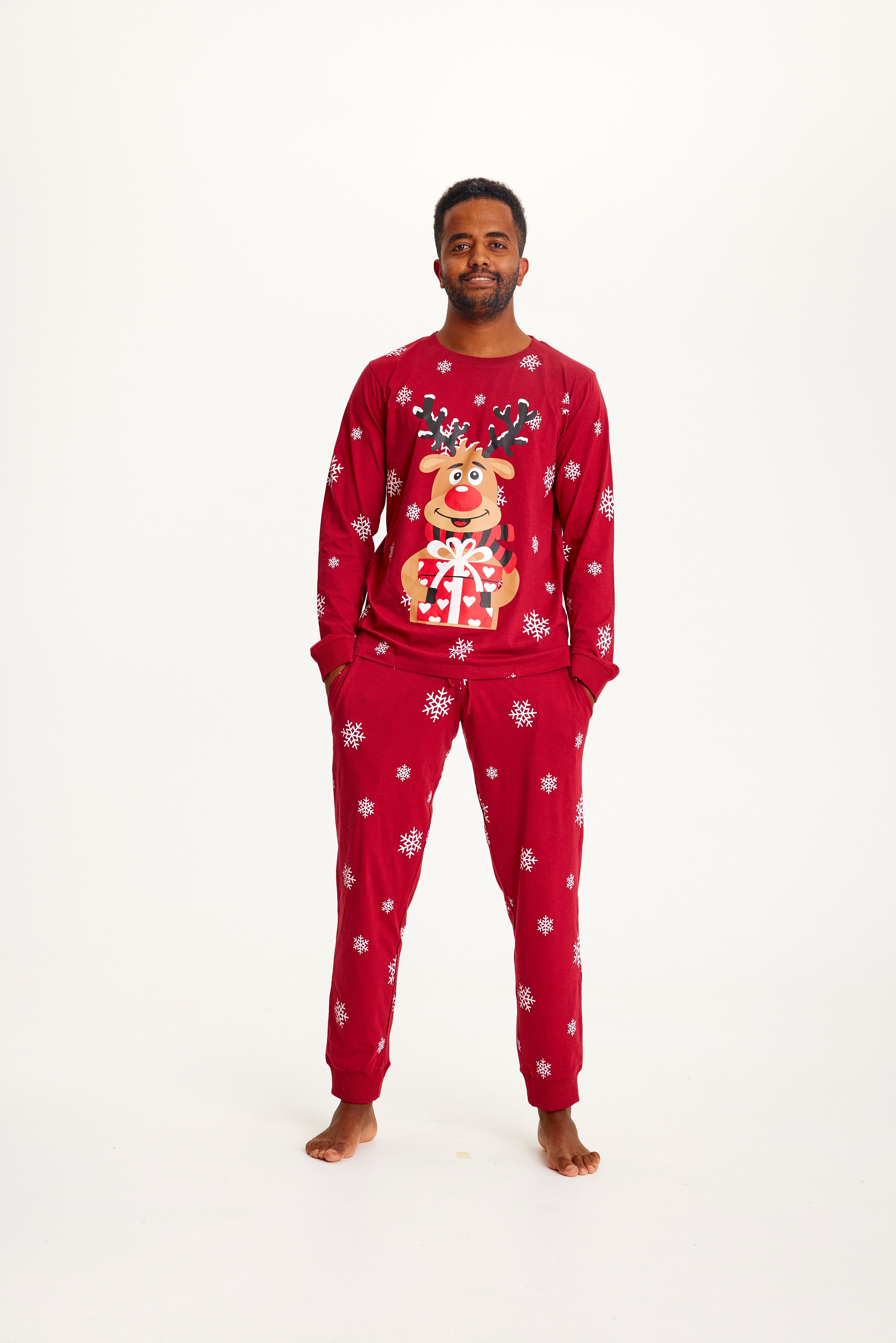 Un homme portant un pyjama de Noël rouge avec Rudolph dessus.