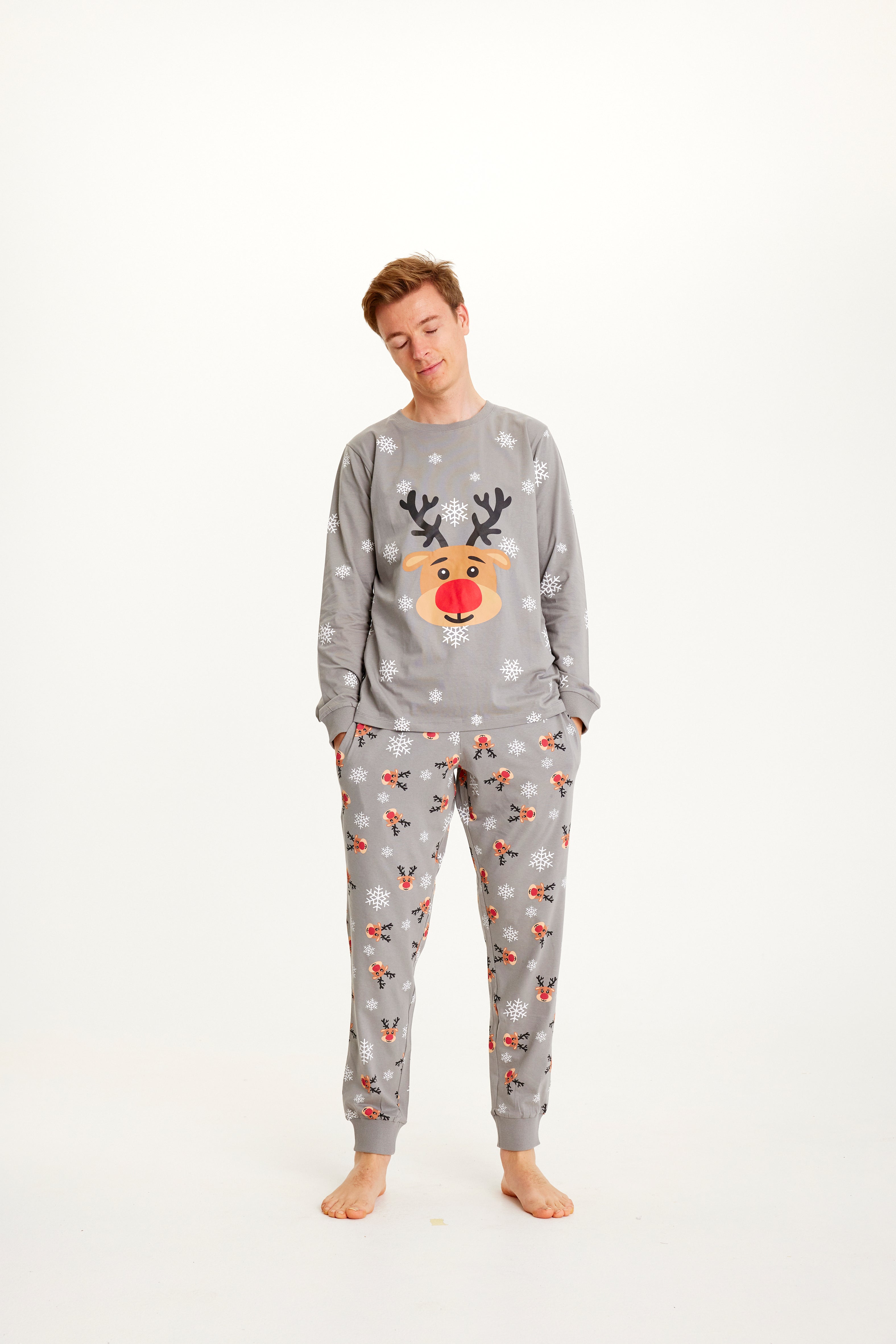 Un homme portant un pyjama de Noël gris avec Rudolph.