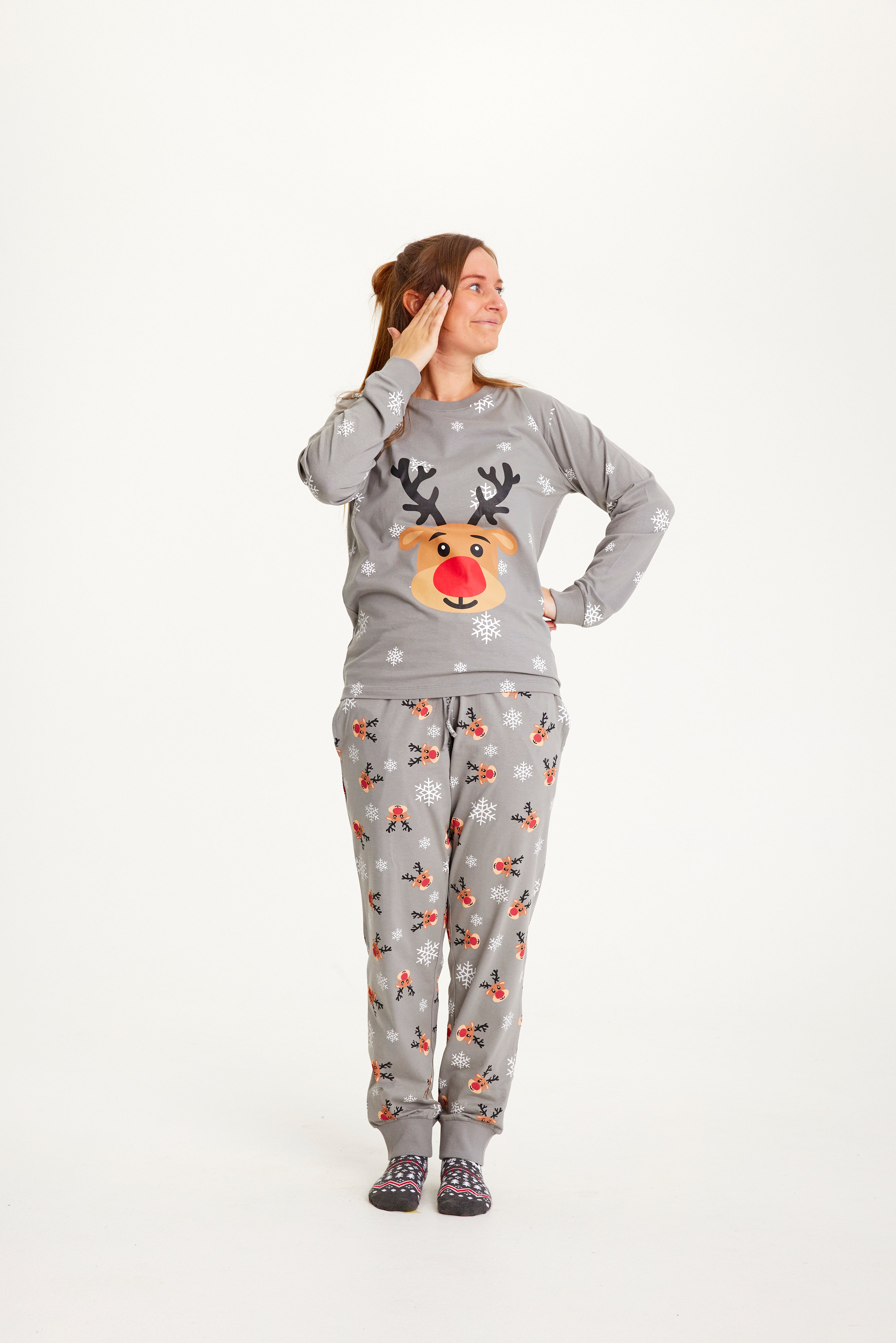 Une femme posant avec un pyjama de Noël gris avec Rudolph.