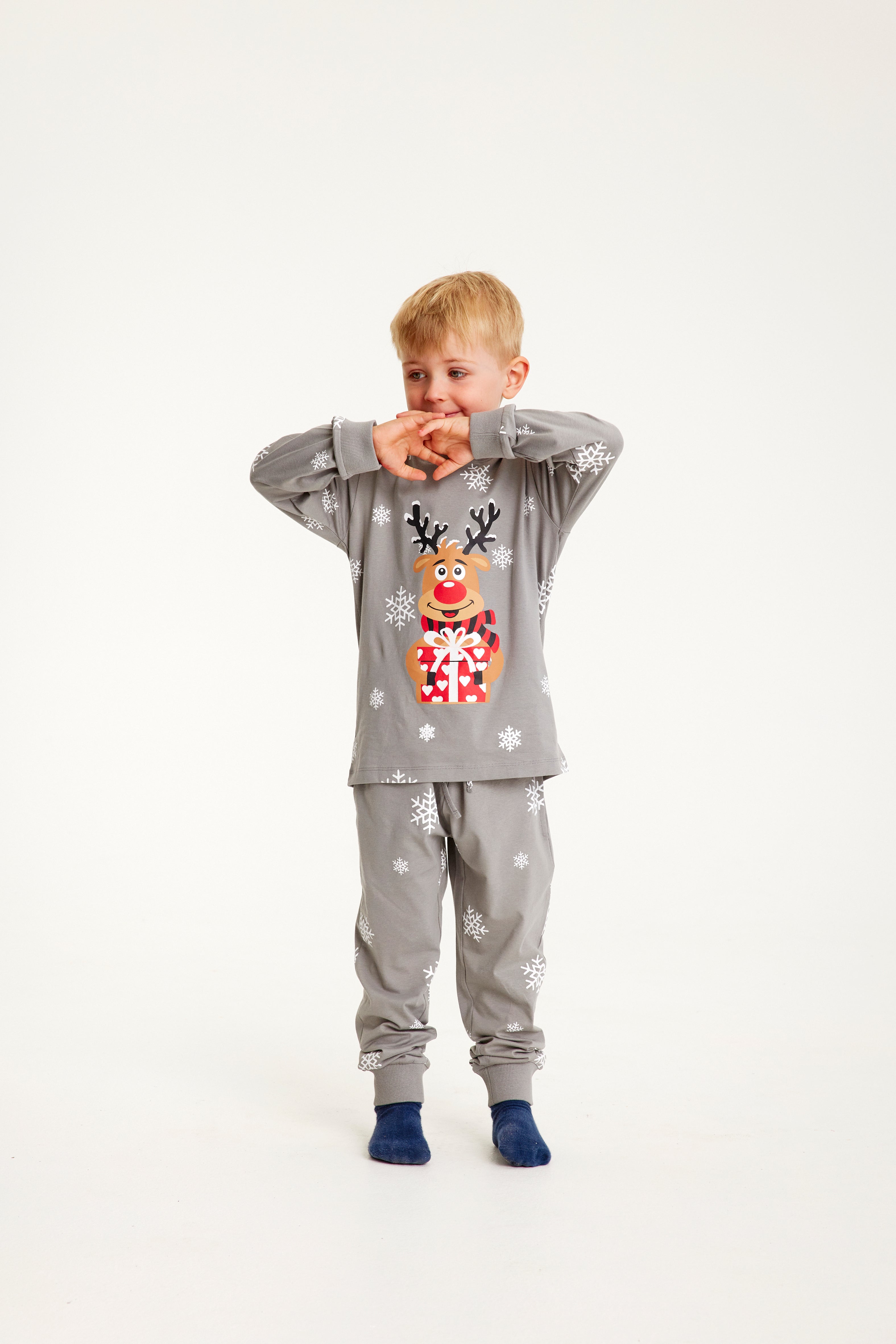 Un enfant portant un pyjama de Noël gris avec Rudolph.