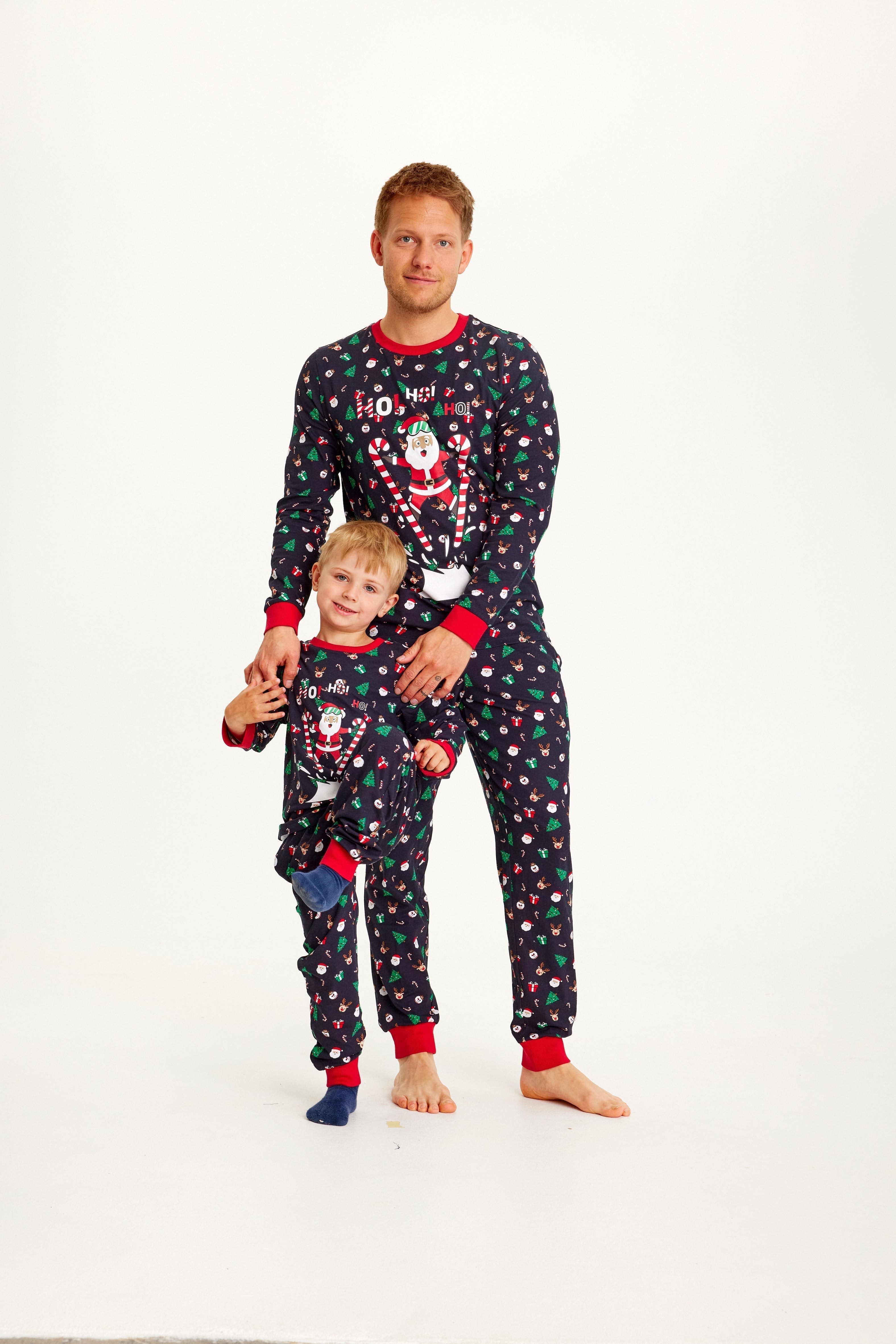 Un homme et un enfant portant un pyjama de Noël à pois avec le Père Noël.