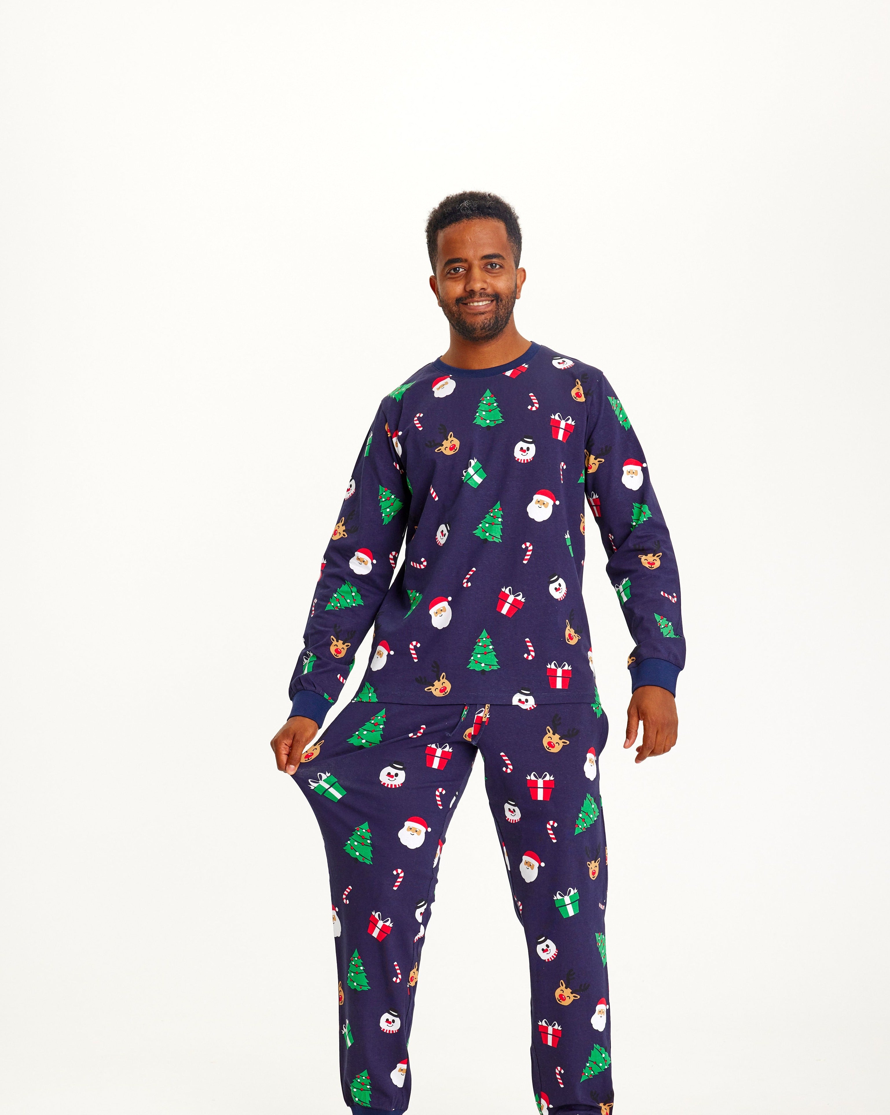 Un homme souriant portant un pyjama de Noël avec des arbres de Noël.