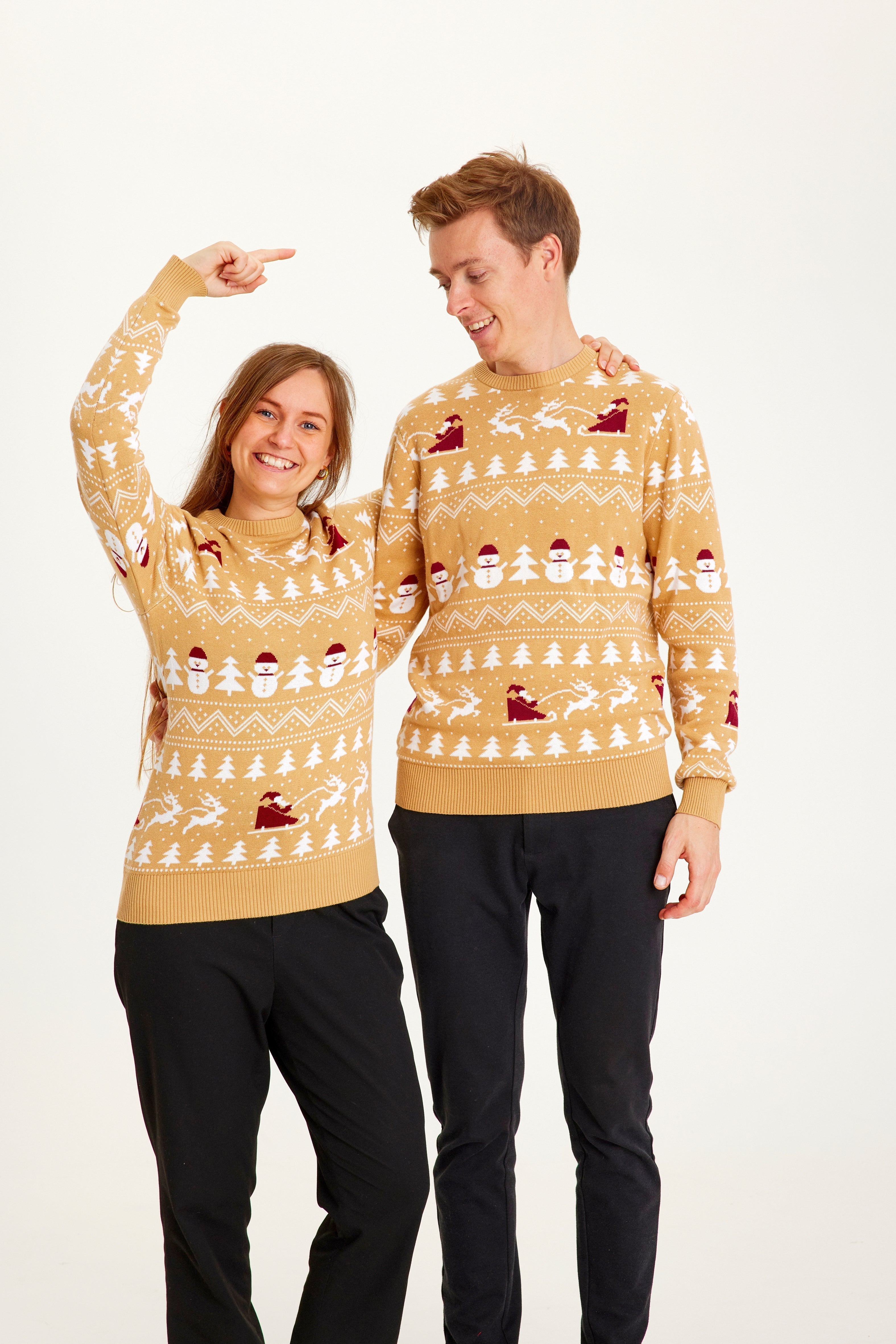 Un couple portant un pull de Noël beige.