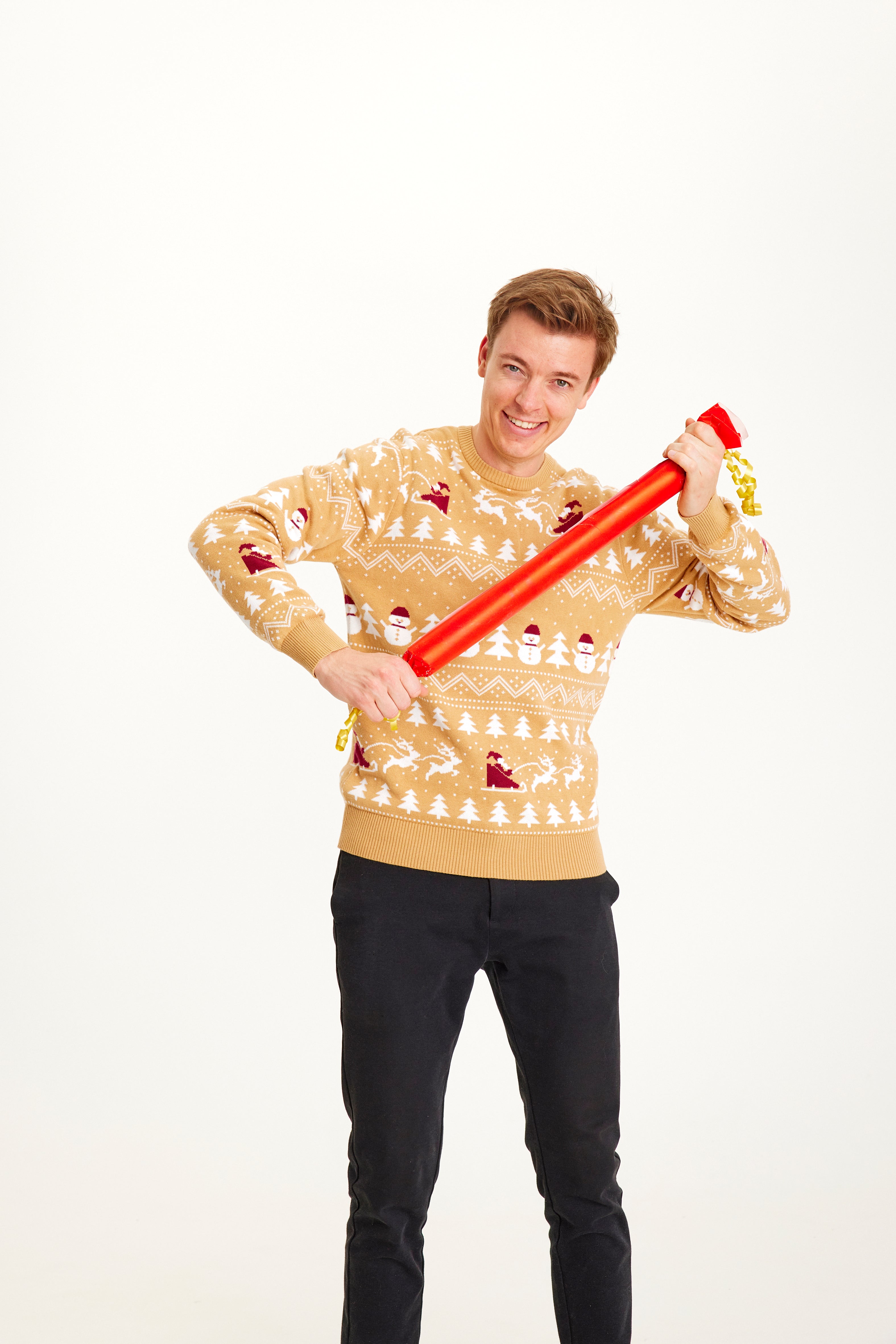 Un homme posant avec un pull de Noël beige.