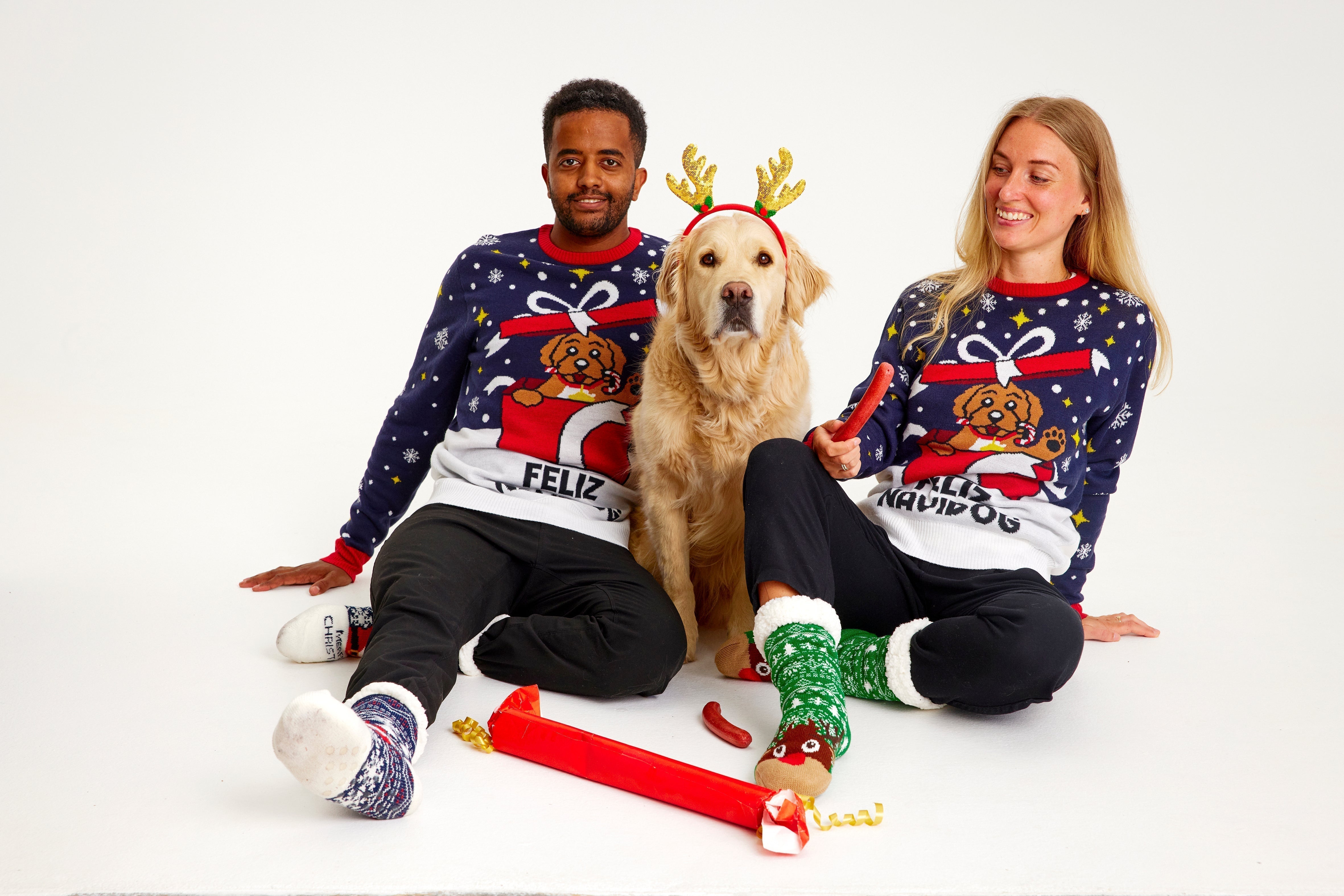 Une famille avec un chien porte un pull de Noël avec un chien dessus.