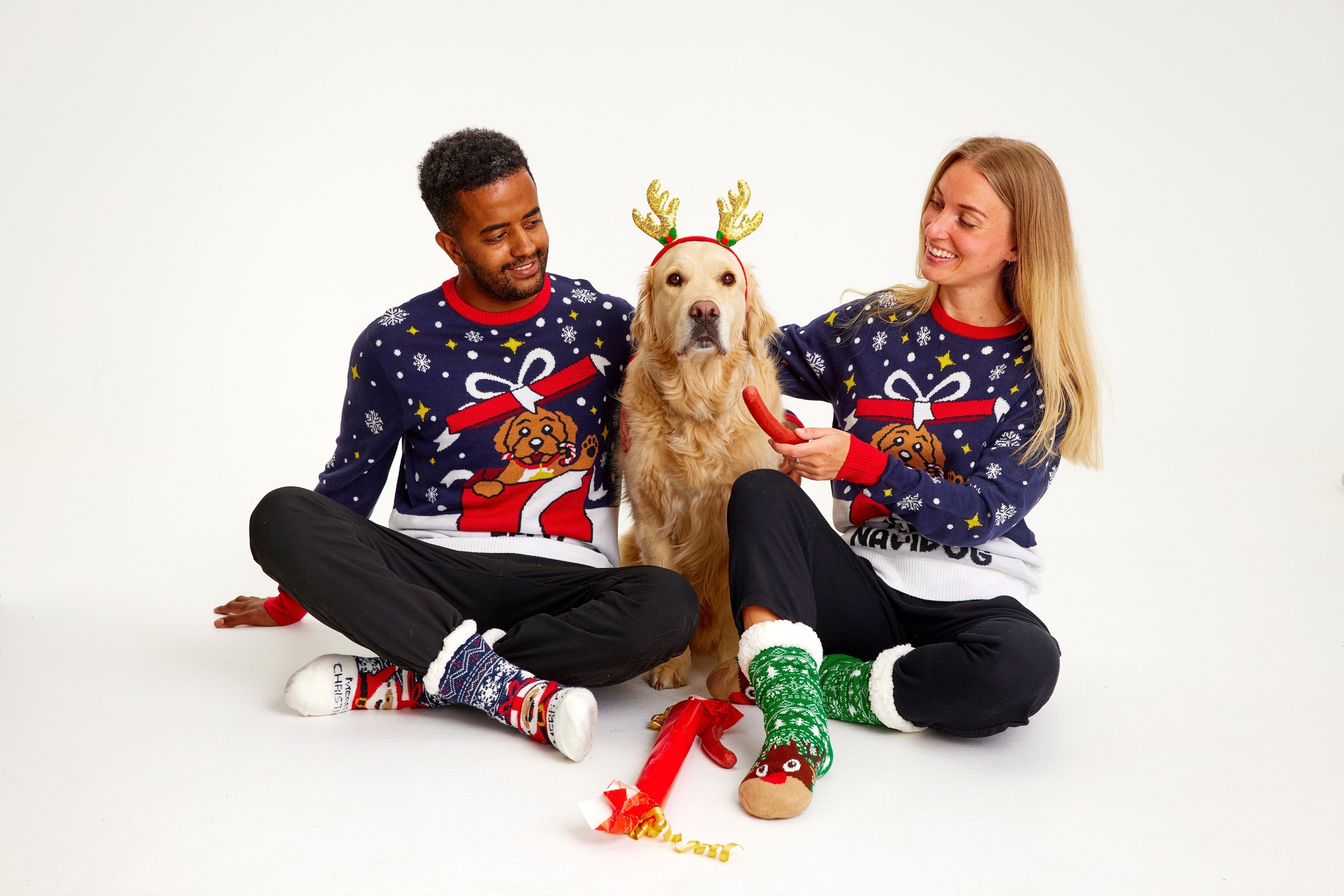 Une famille avec un chien porte un pull de Noël avec un chien dessus.