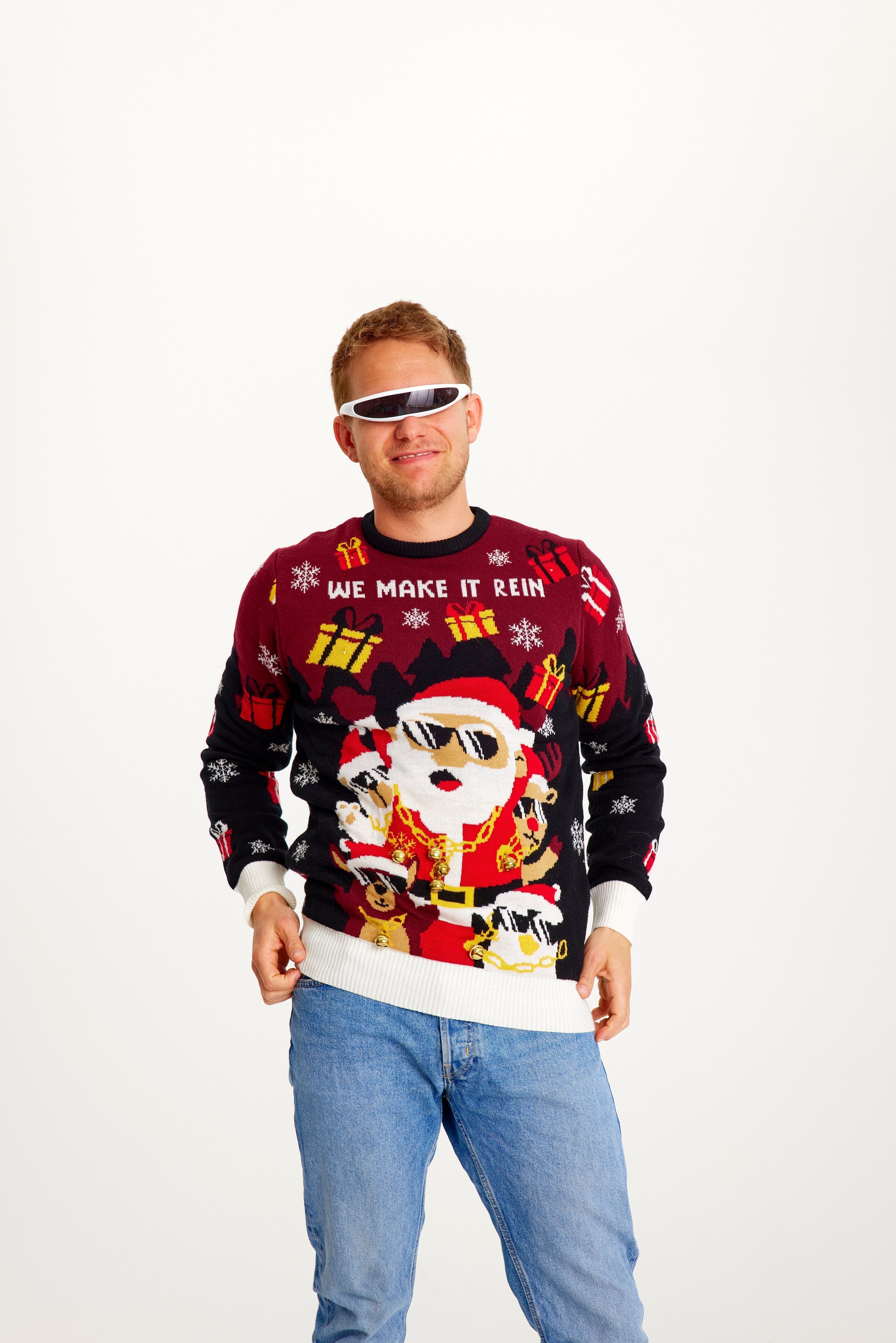 Un homme souriant portant un pull de Noël rouge et noir avec le Père Noël et des lumières.