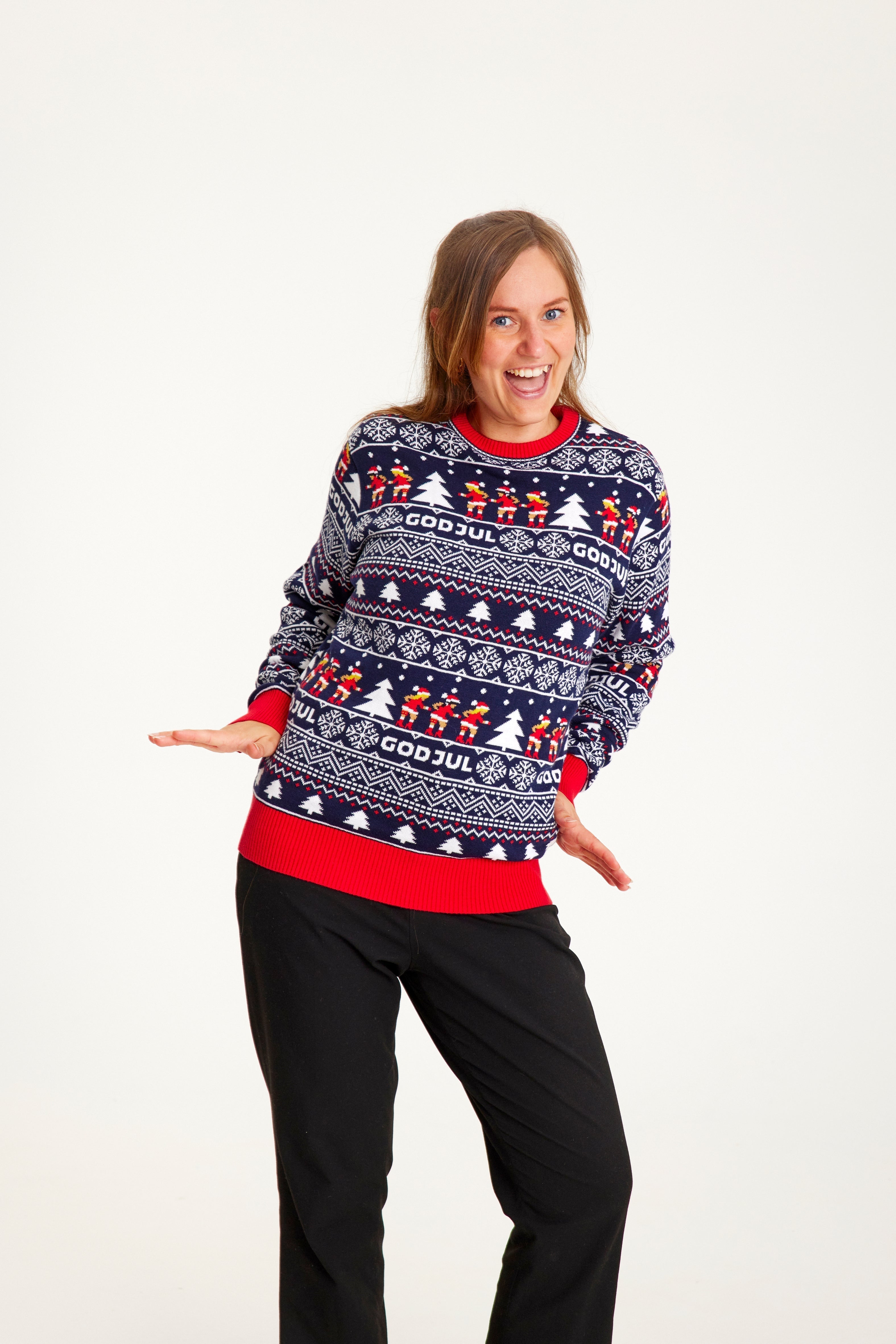 Une femme souriante portant un pull de Noël à motifs bleus.