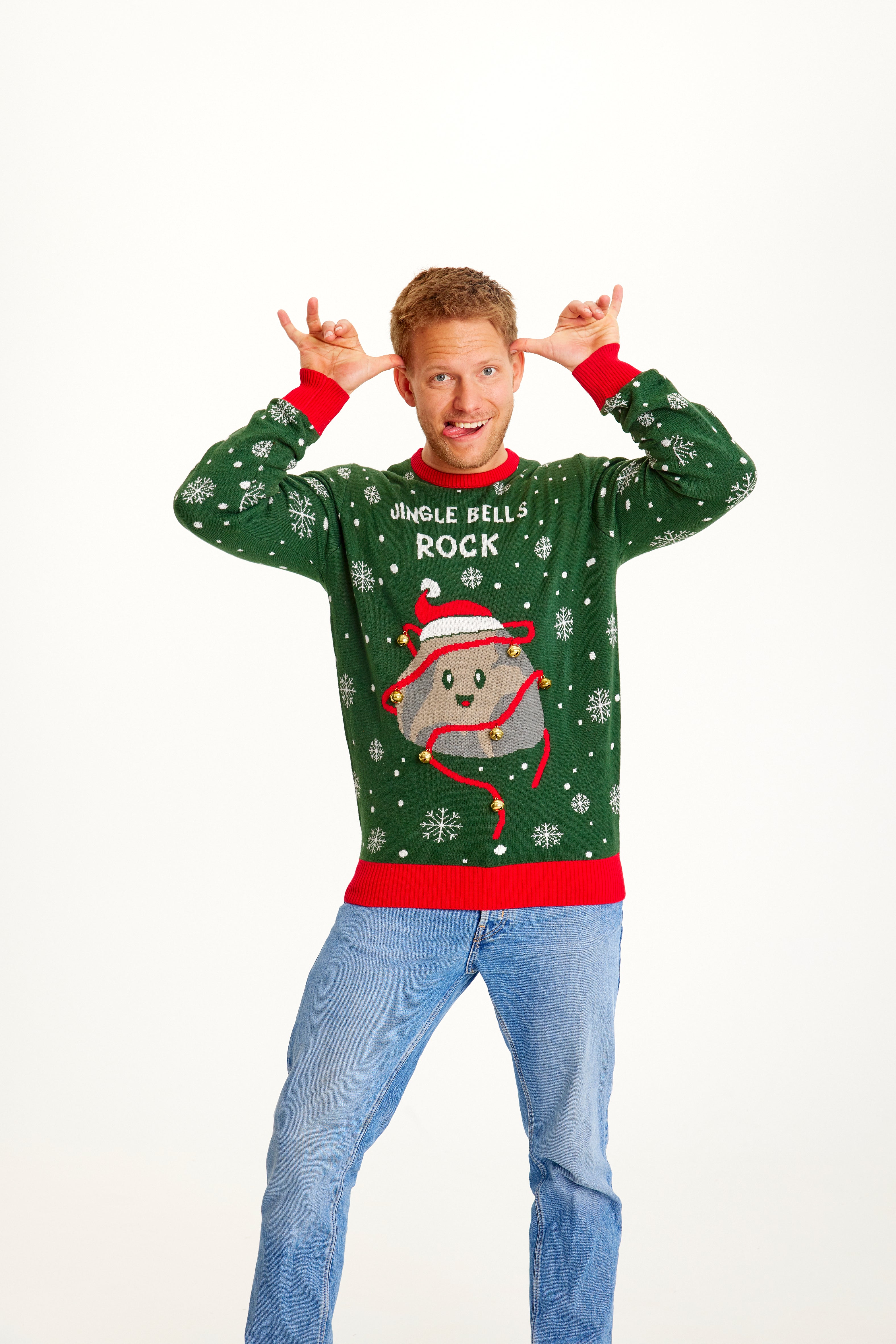 Un homme pose vêtu d'un pull vert de Noël orné d'une pierre.