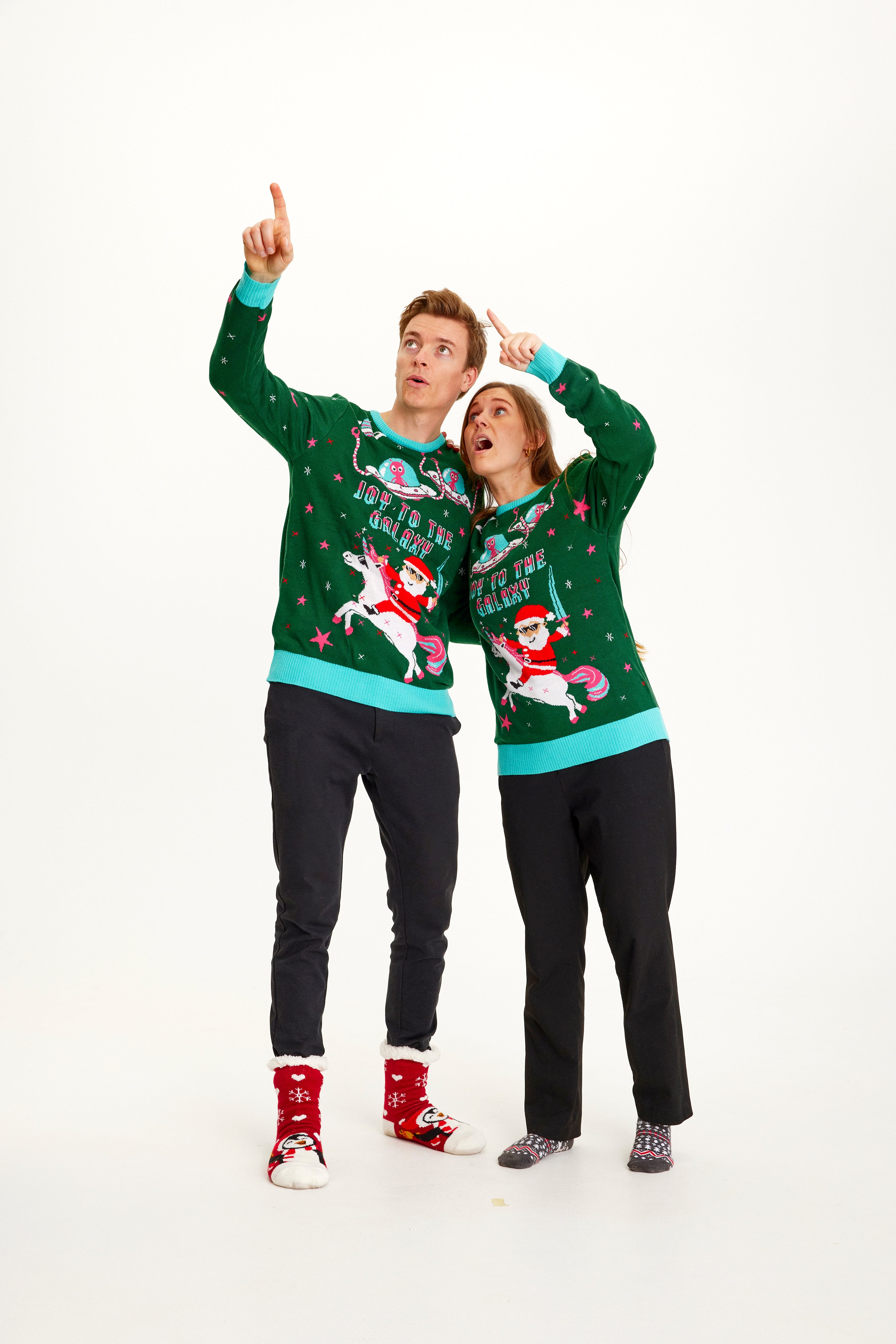 Un couple posant avec un pull de Noël vert avec la citation 