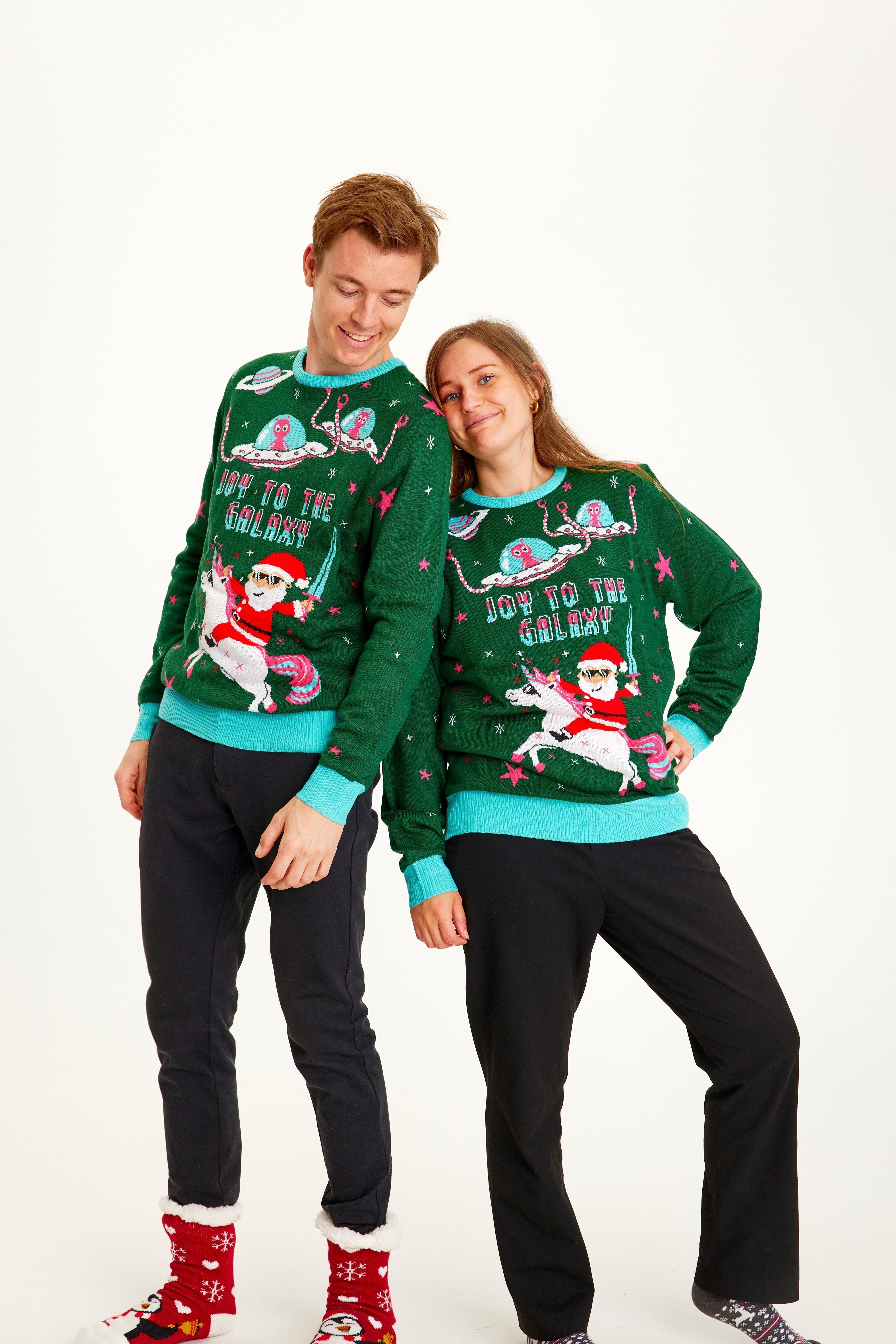 Un couple portant un pull de Noël vert avec la citation 
