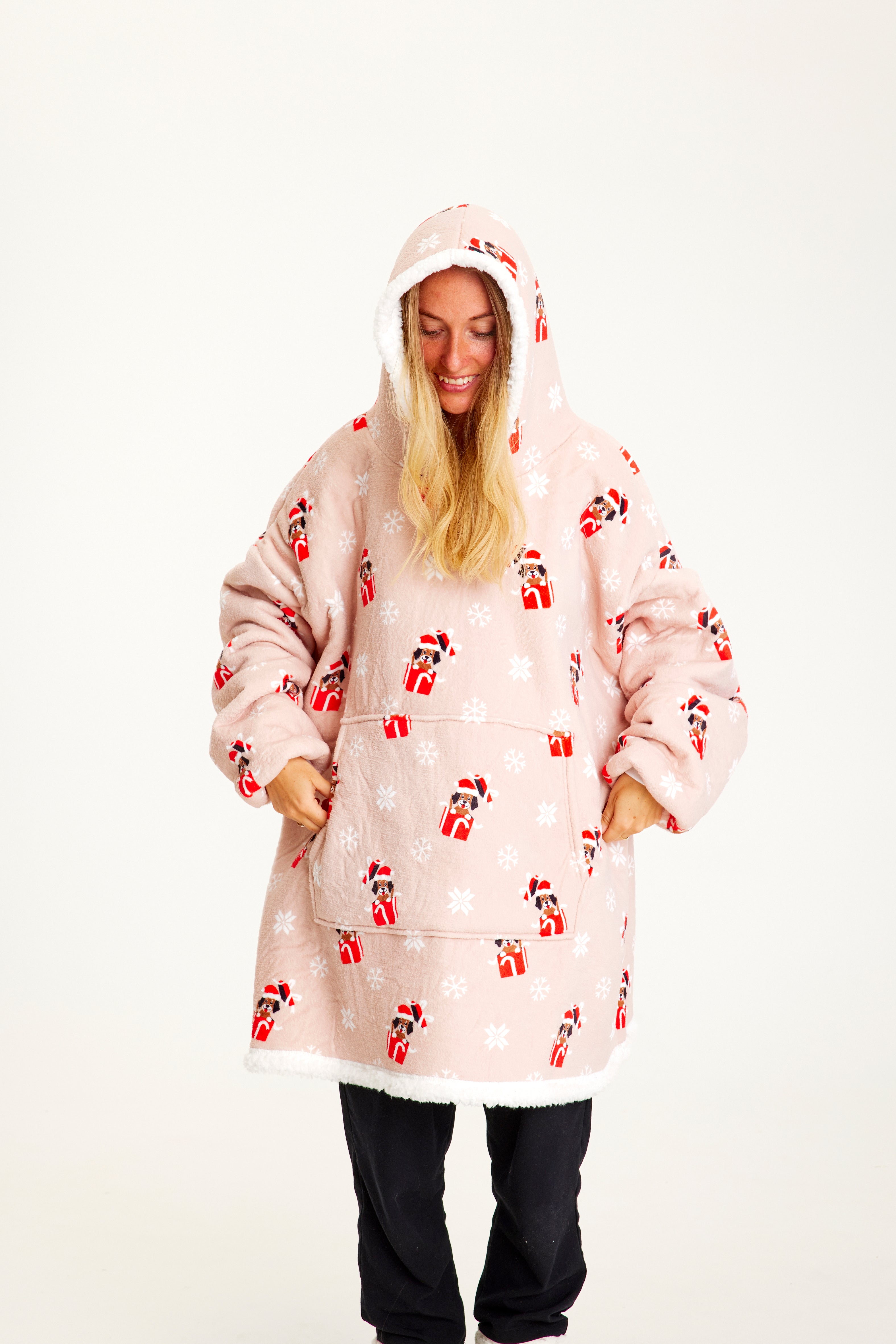 Une femme portant un sweat à capuche de Noël rose avec des chiens.