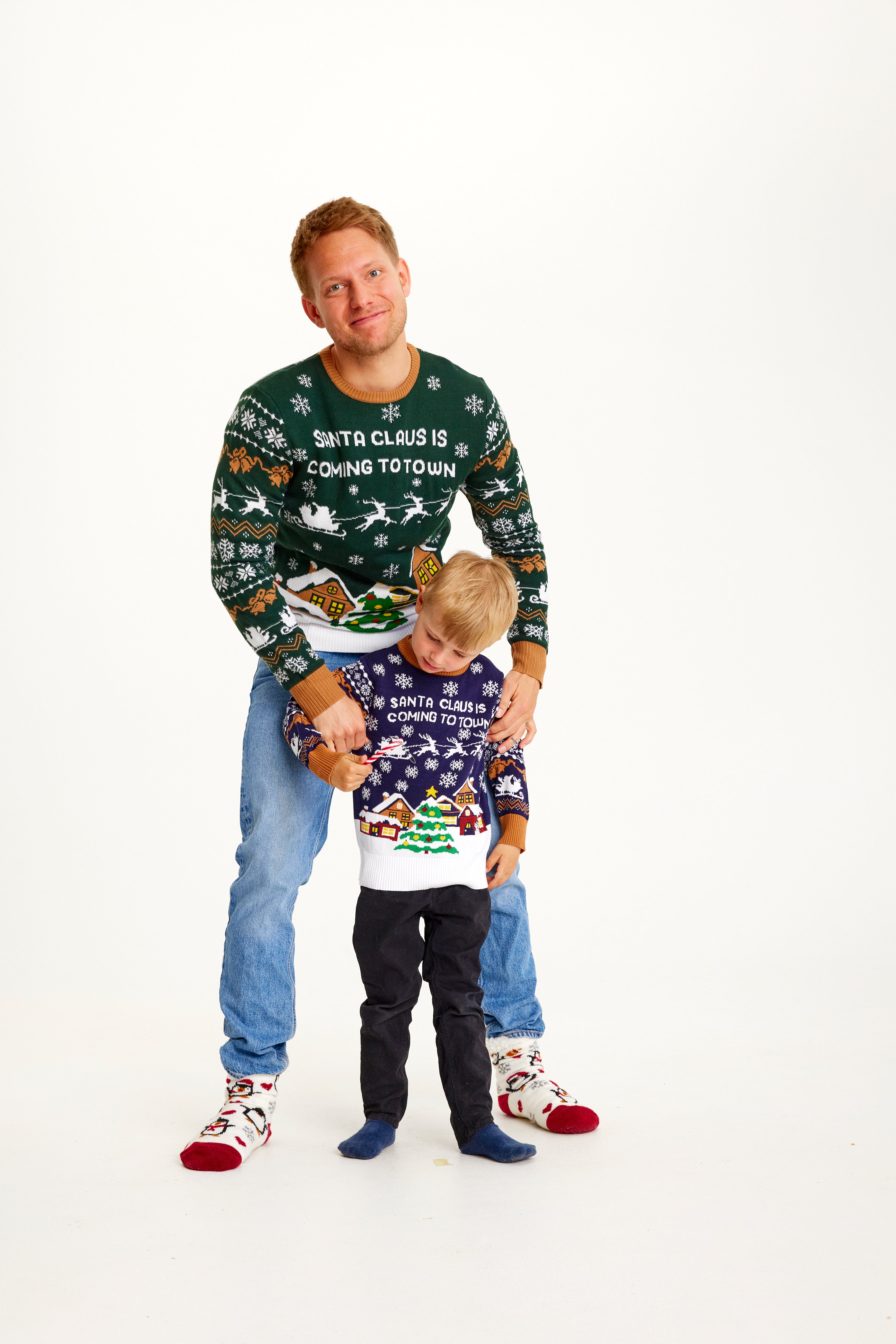 Un homme et un enfant portant un pull de Noël avec un sapin de Noël.