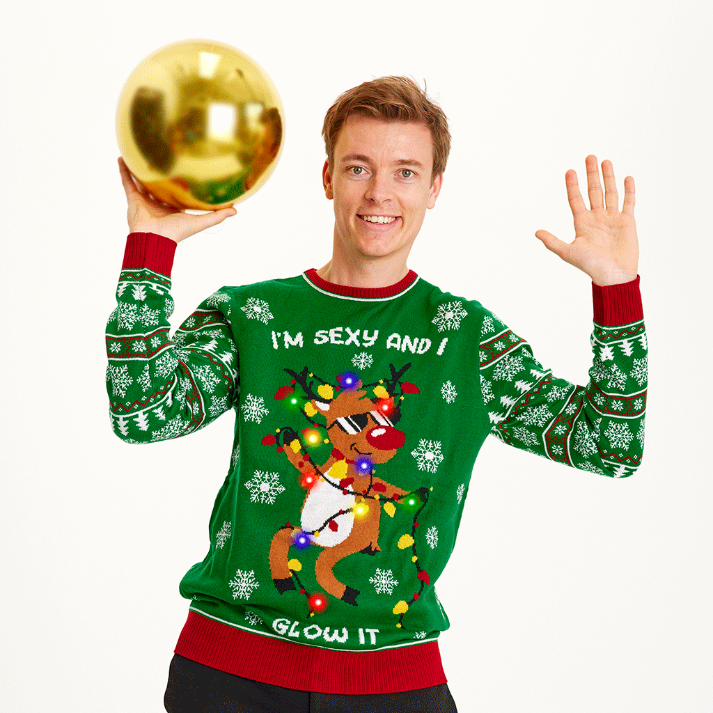 Un homme portant un pull vert de Noël avec un renne dansant et des lumières.