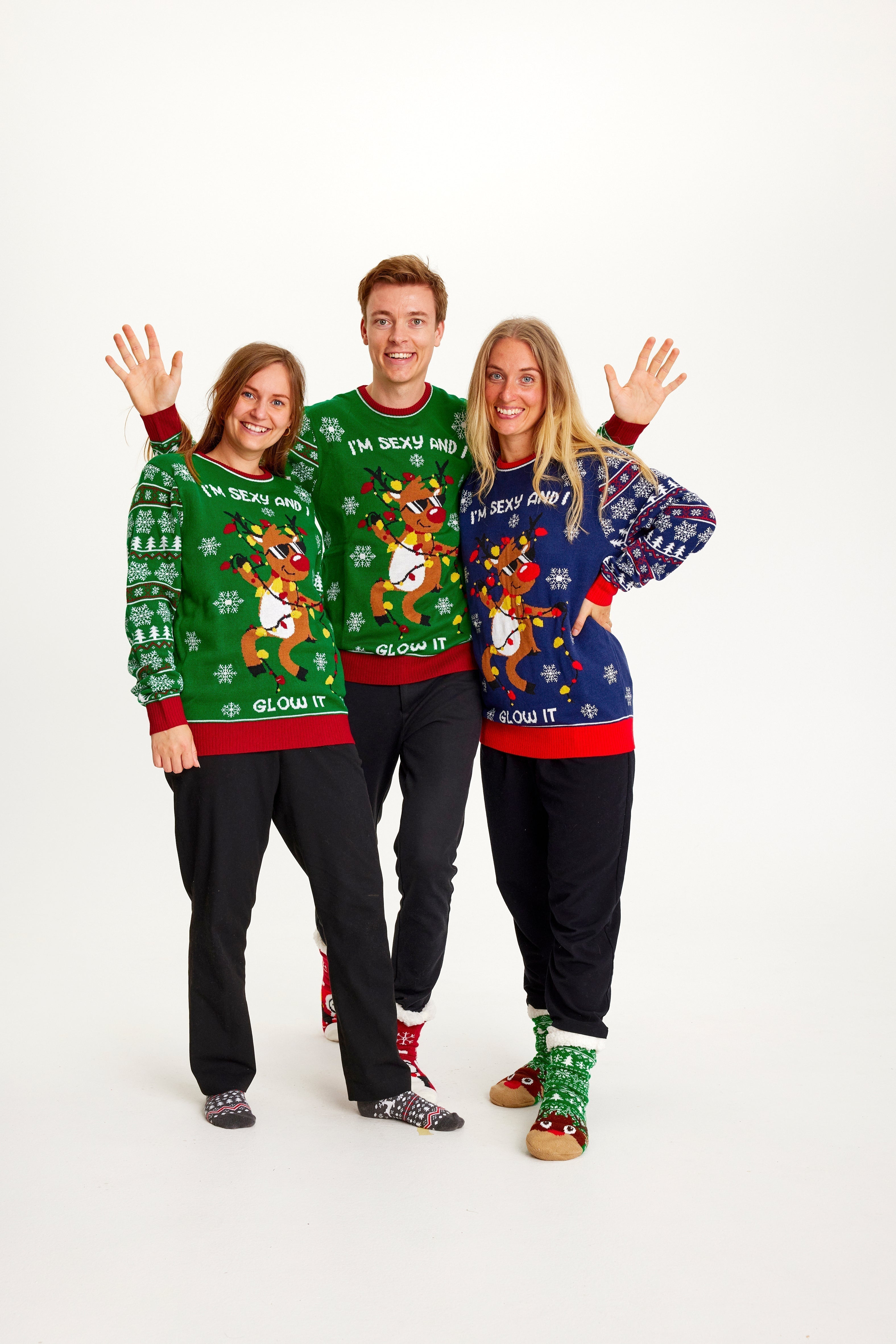 Trois personnes portant un pull de Noël avec un renne dansant et des lumières.