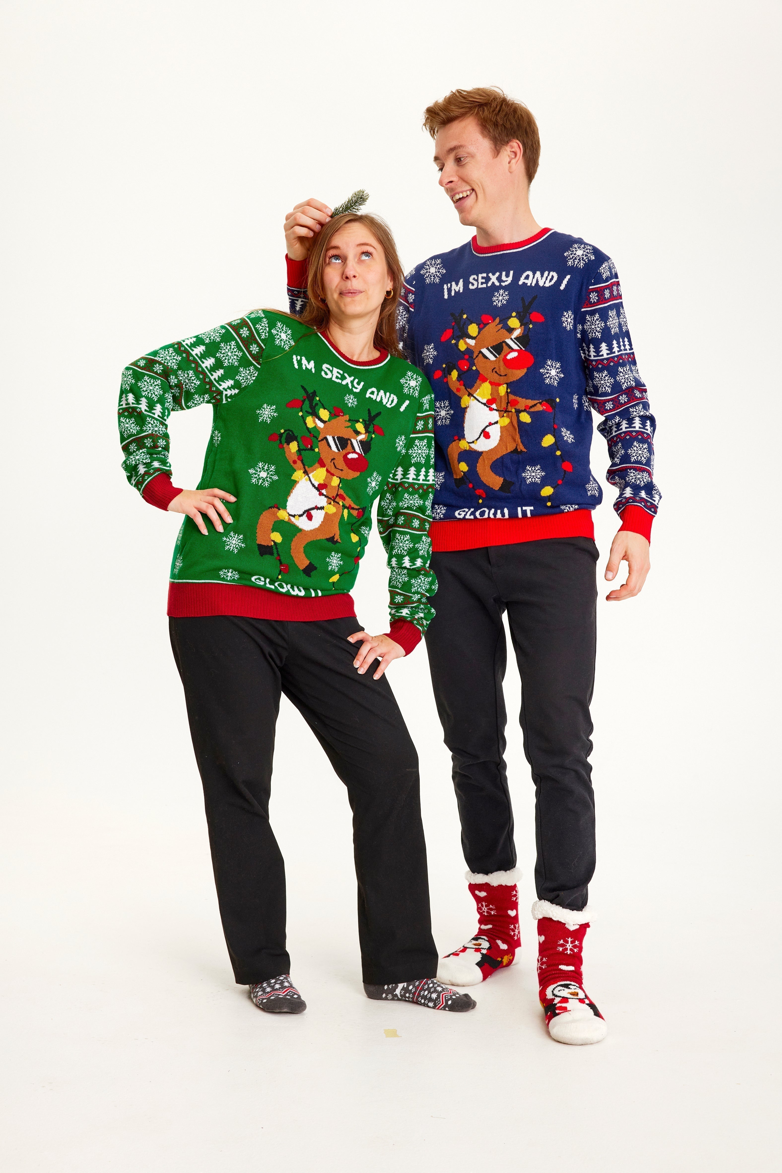 Un couple portant un pull de Noël avec un renne dansant et des lumières.