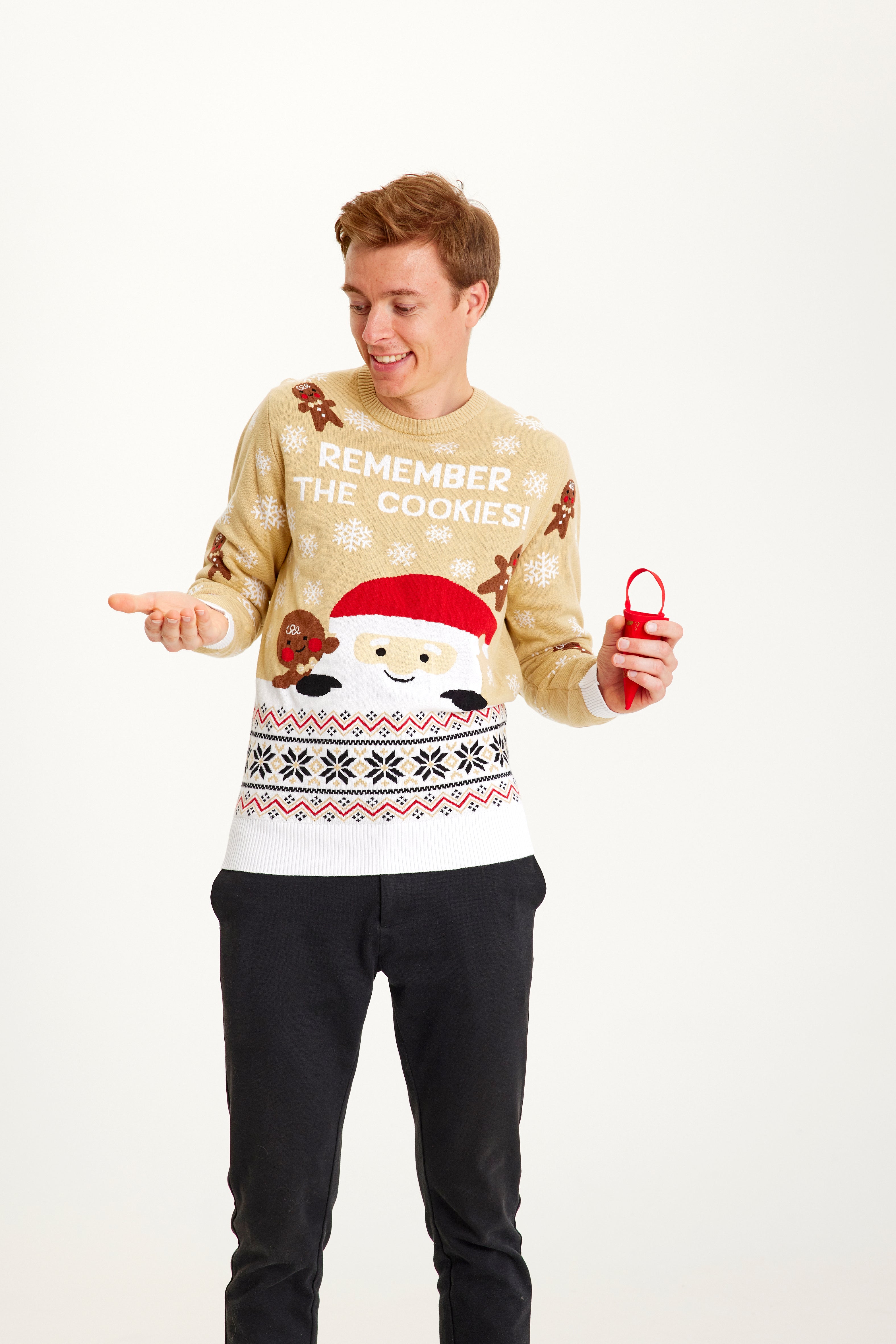 Un homme posant portant un pull de Noël beige.